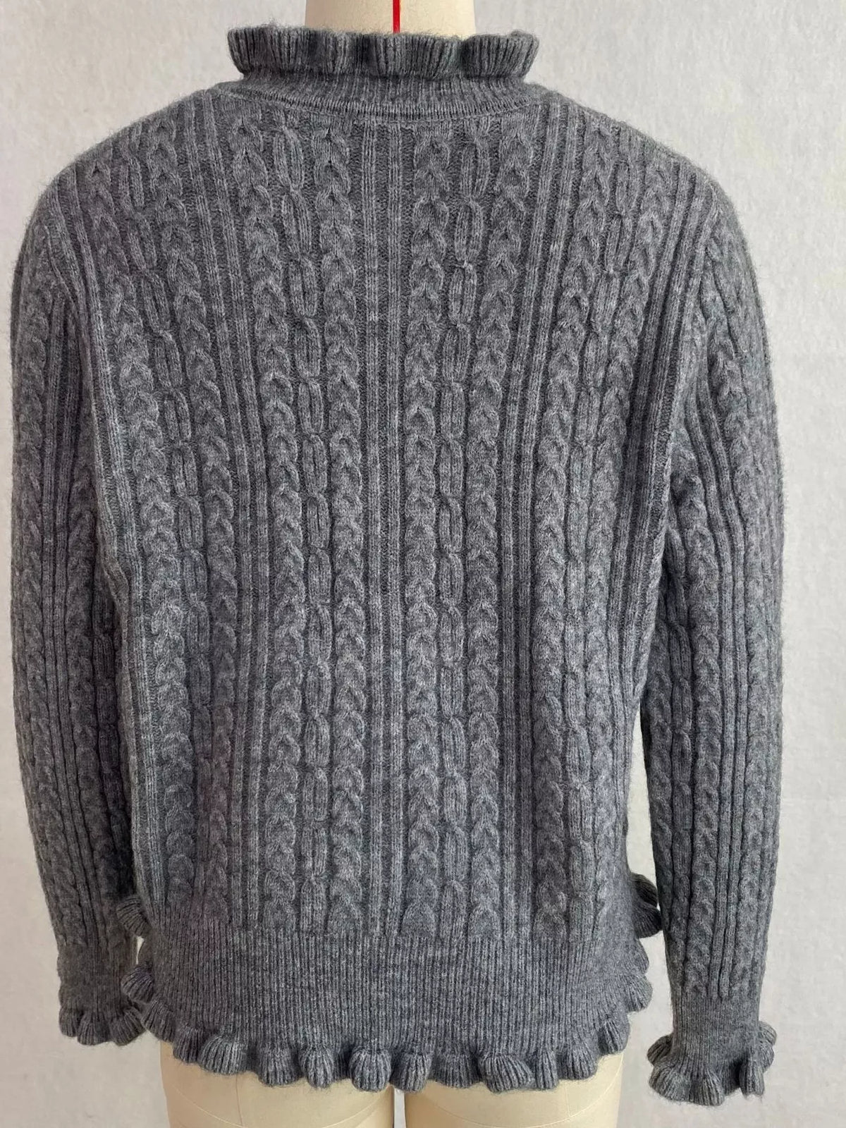 Gray cable-knit ruffle-trim cardigan, back on dress form.