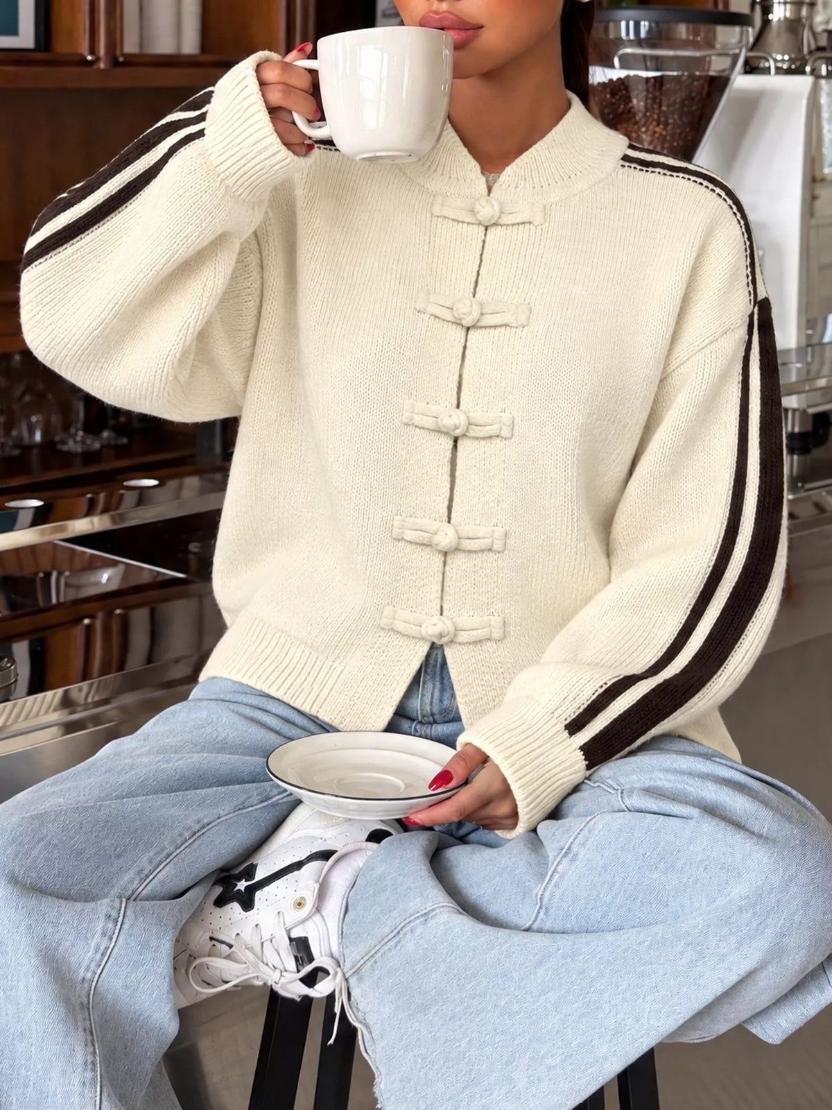 Cream Chinese knot button cardigan with sleeve stripes, seated front view