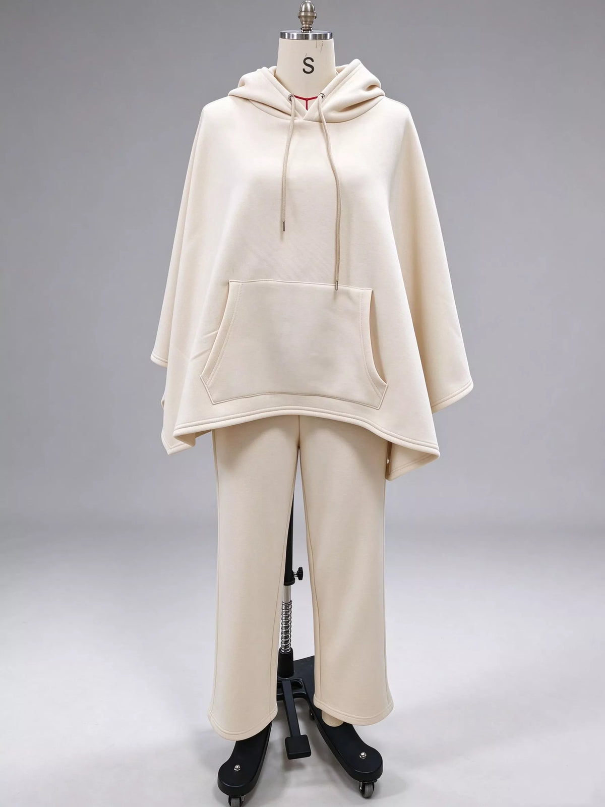 Cream hooded poncho and wide-leg pants set, front on dress form.