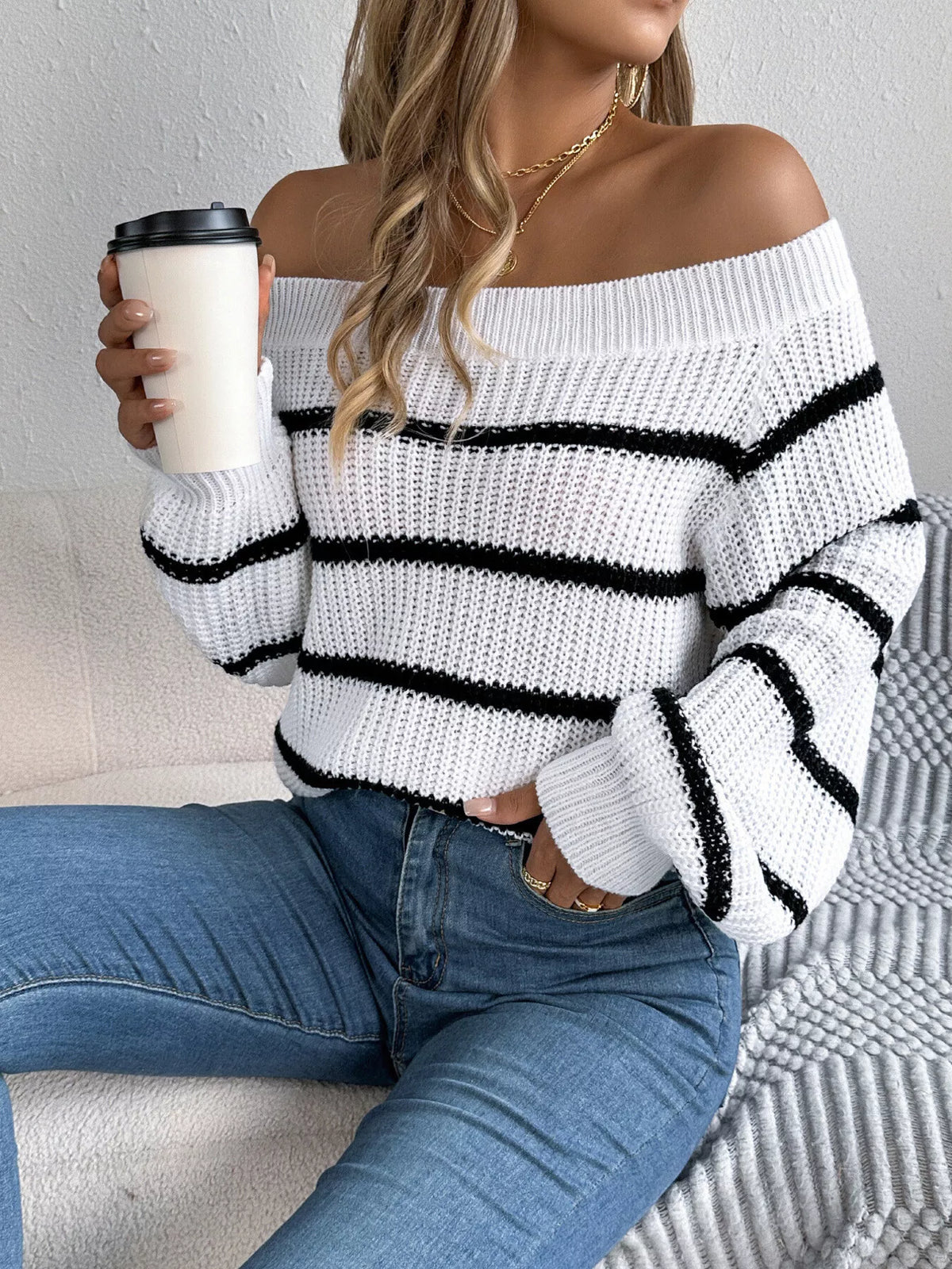 White off-shoulder striped sweater, seated front view.