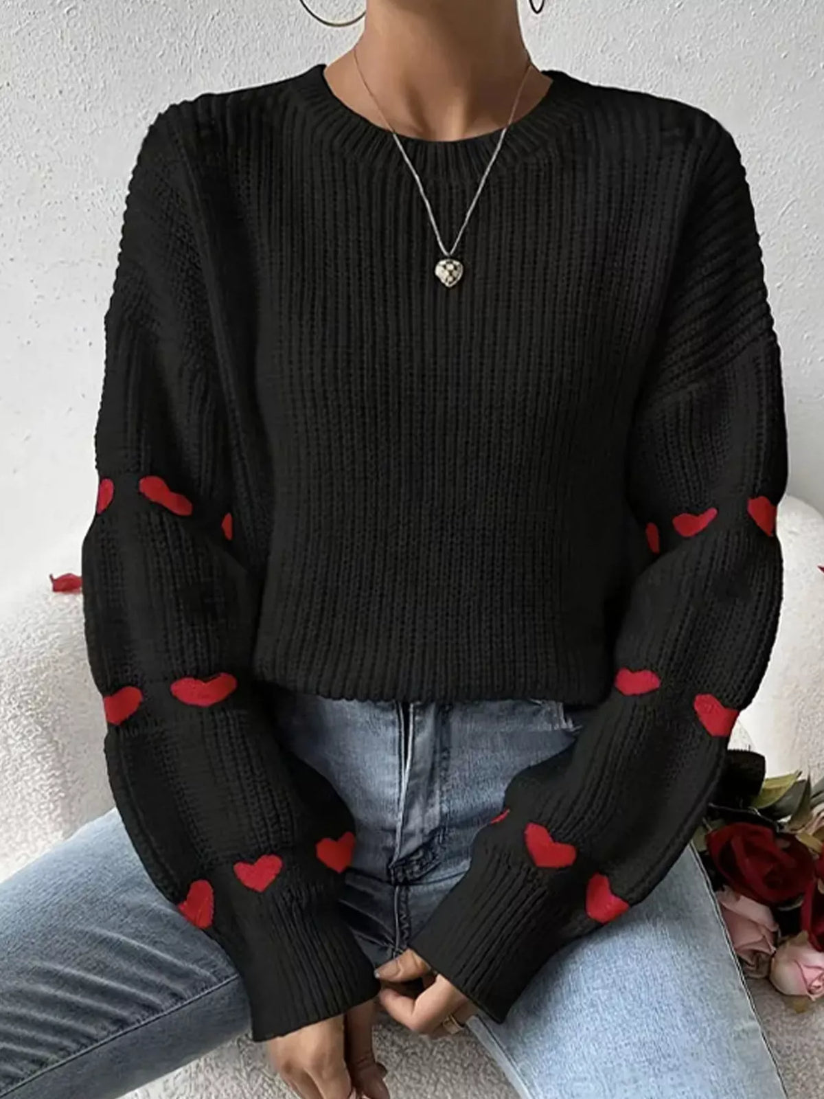 Black and red heart-sleeve dropped-shoulder sweater, seated front view.