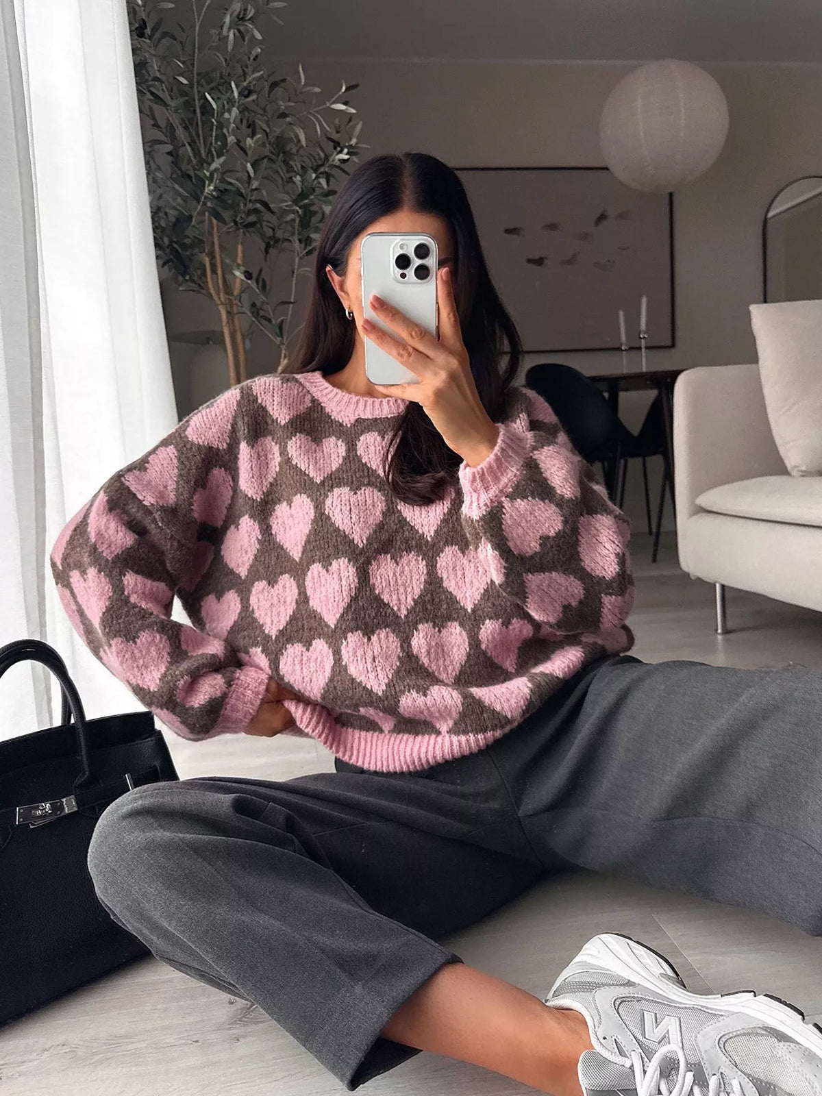 Brown and pink allover heart dropped-shoulder sweater, seated front view.