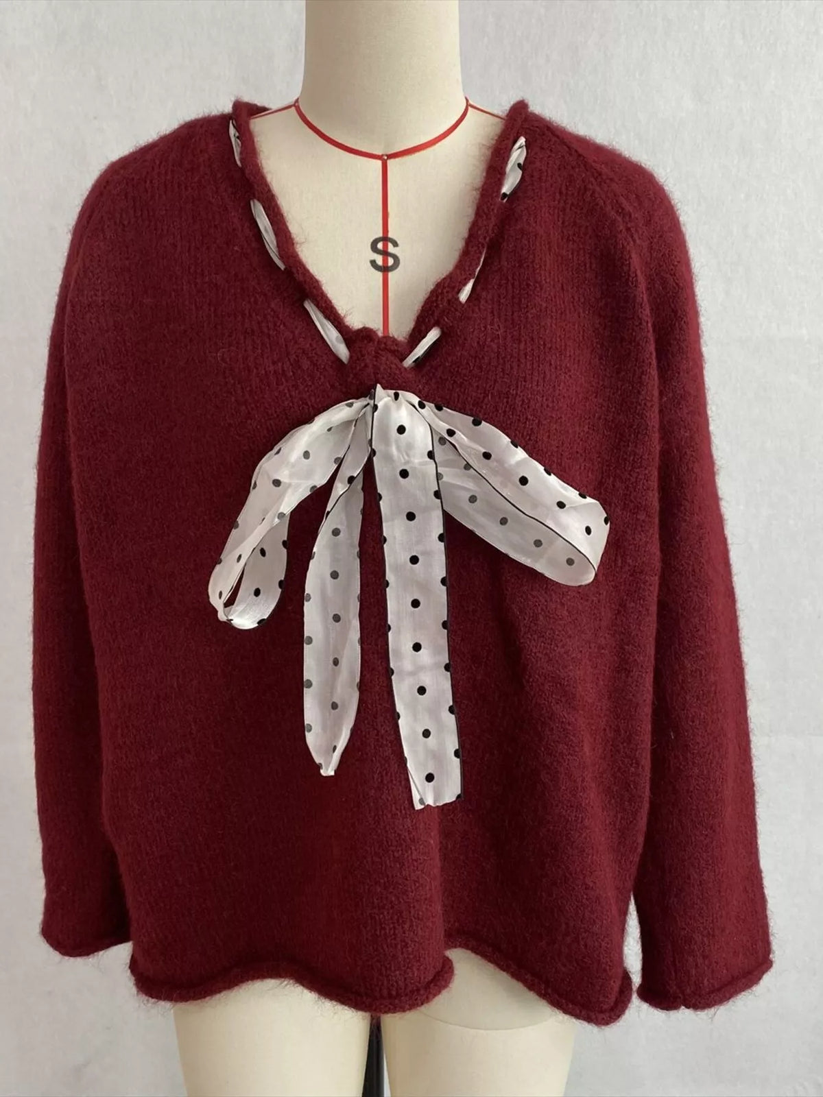 Burgundy v-neck knit top with polka dot ribbon tie, front on dress form.