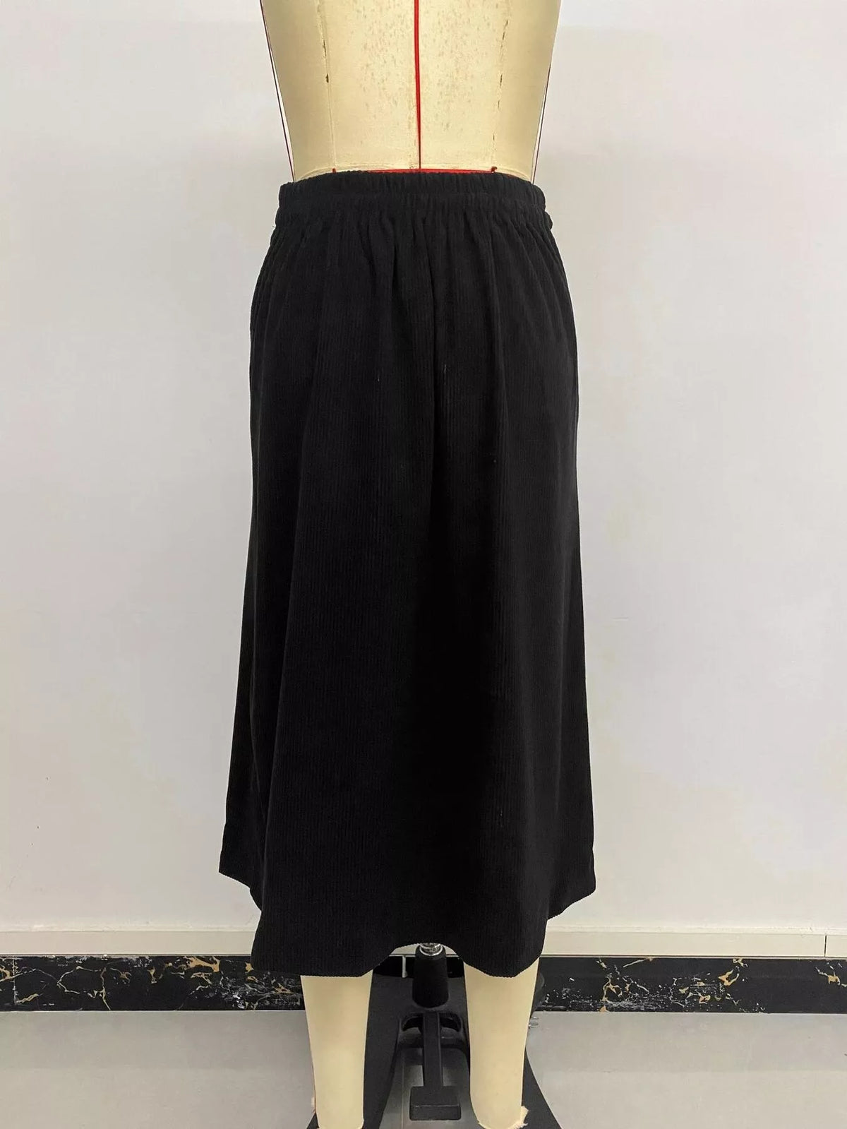 Black corduroy button-front midi skirt, back on mannequin
