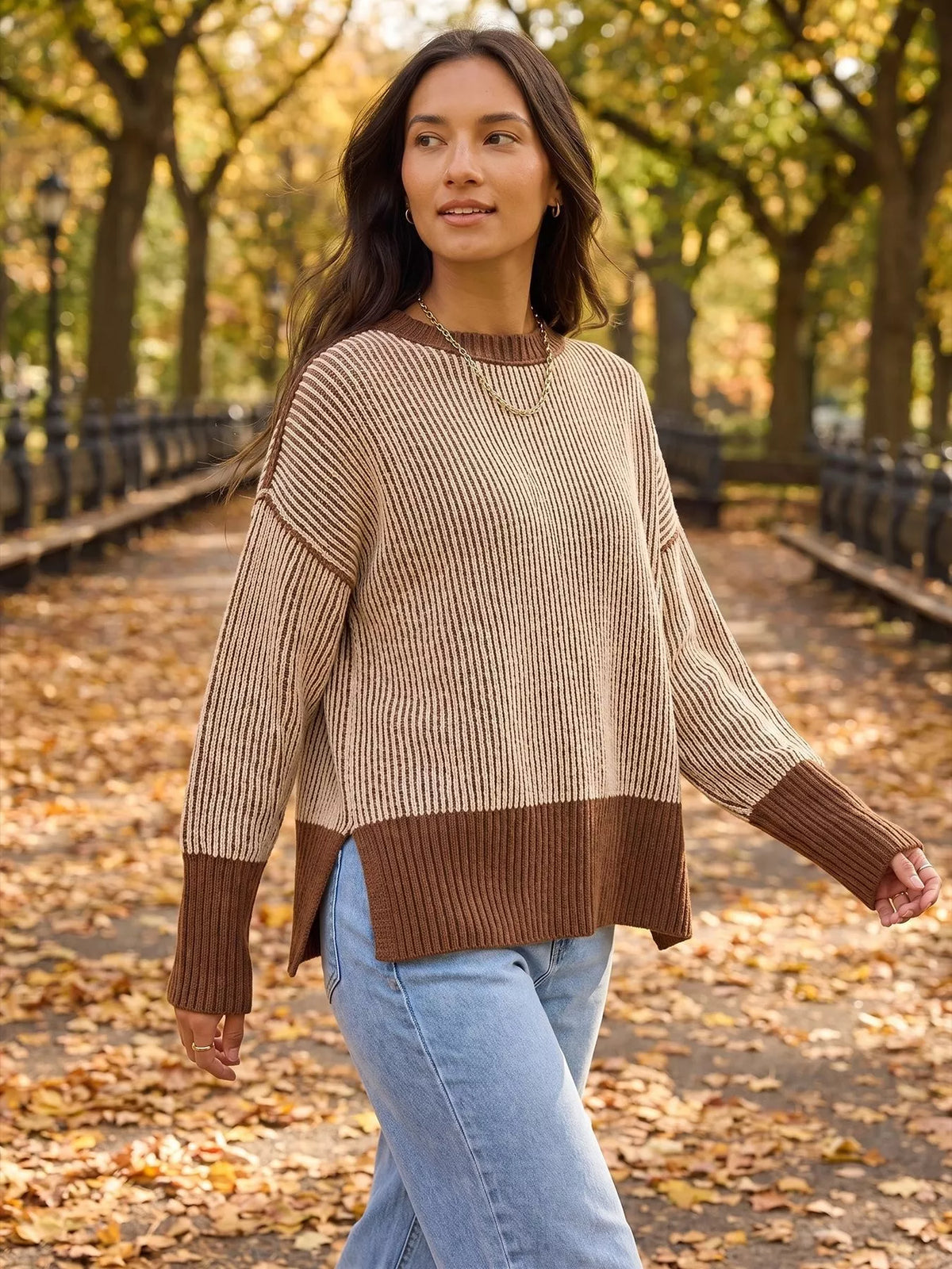 Beige and brown ribbed side-slit sweater with contrast trim, walking view showing side slit.