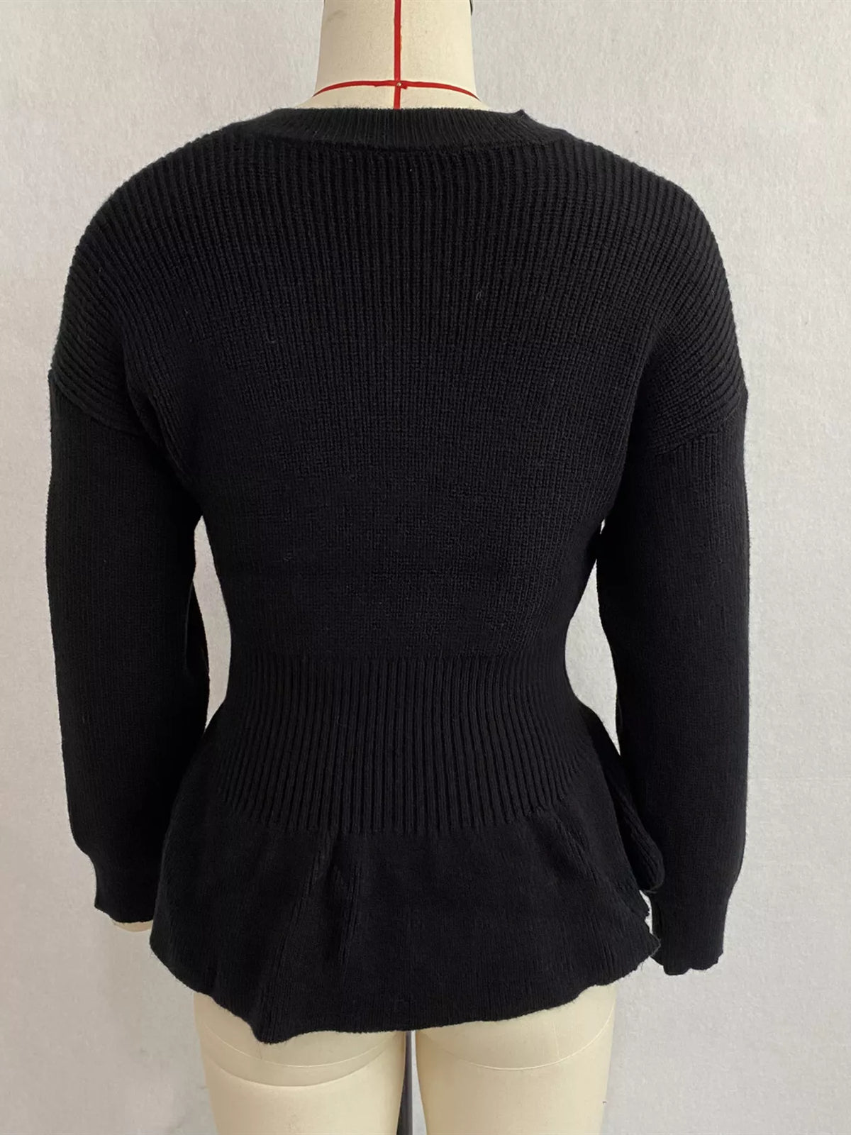 Black v-neck peplum-hem knit sweater, back on dress form.