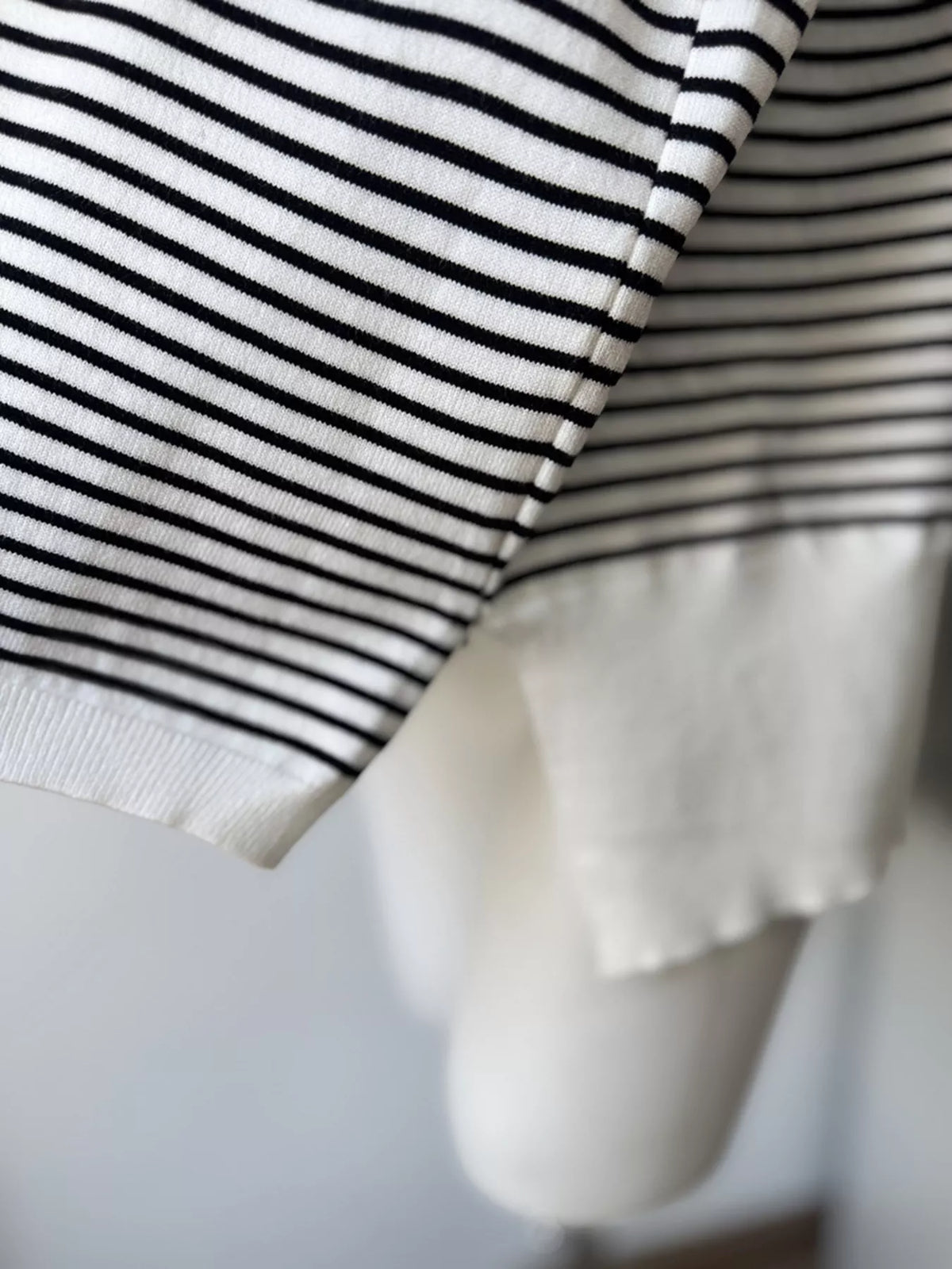 Striped round-neck knit top in white and black, ribbed hem detail