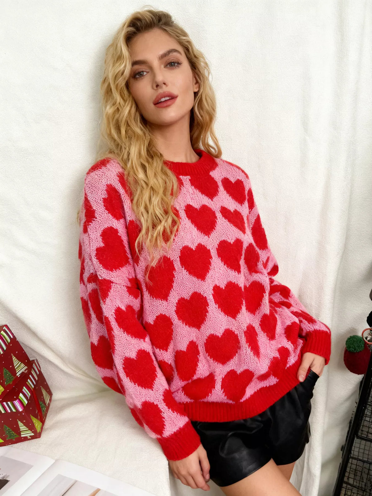 Pink and red allover heart dropped-shoulder sweater, angled front view.