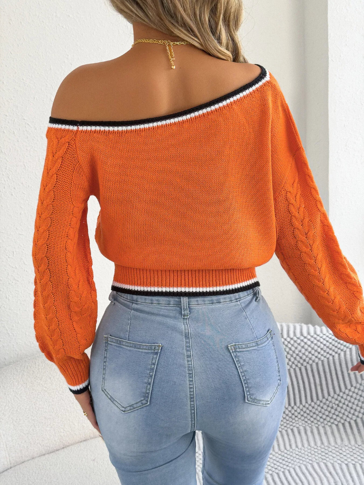 Orange one-shoulder cable knit sweater with striped trim, back view