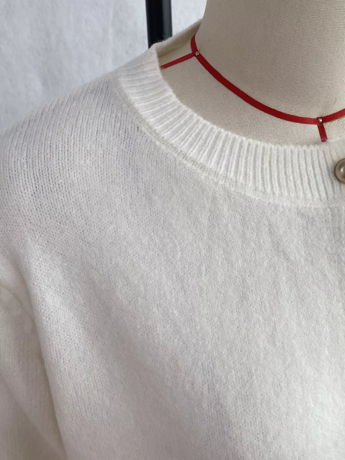 White round-neck button-front knit cardigan, ribbed neckline detail.