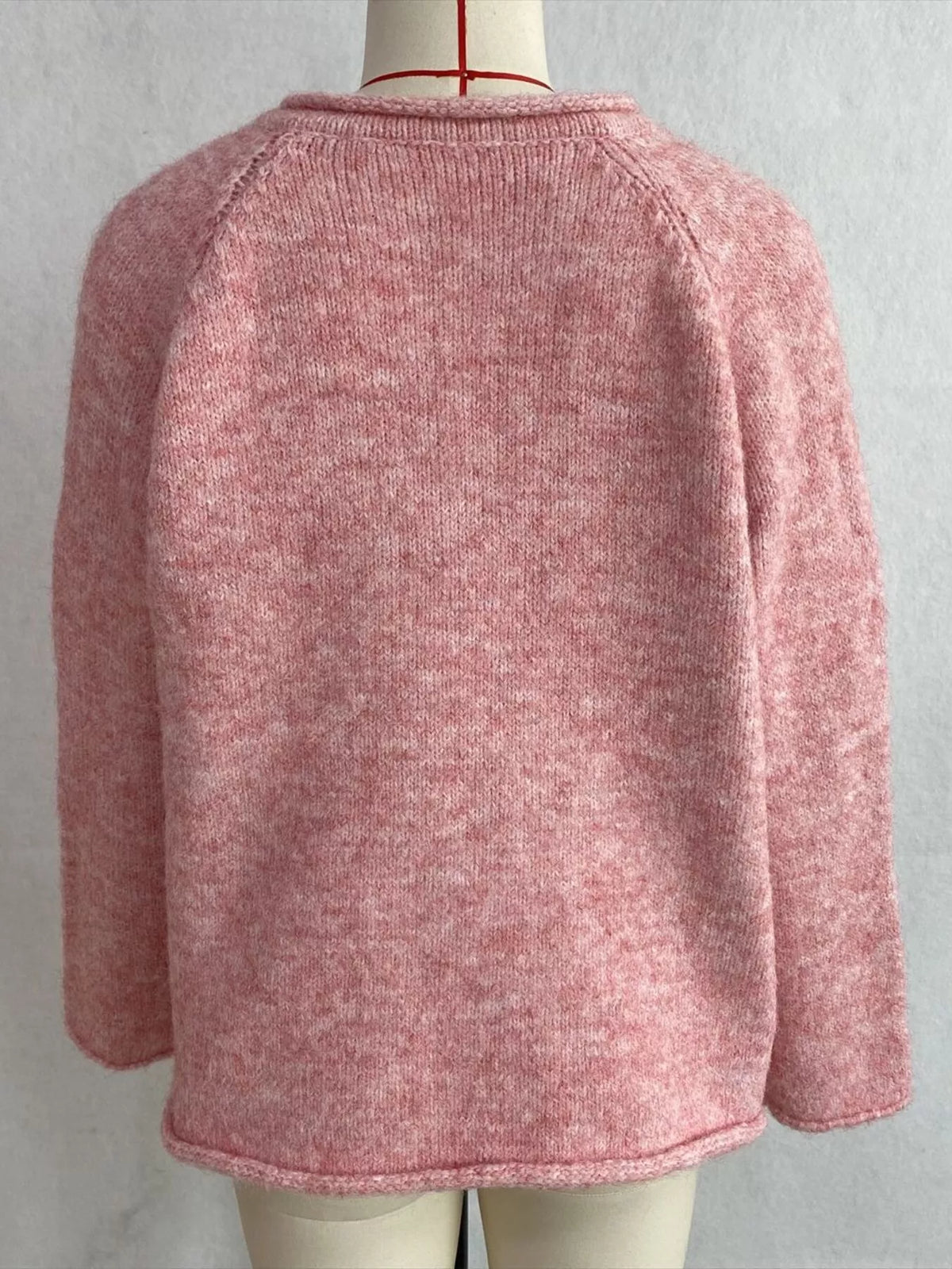 Pink v-neck knit top with polka dot ribbon tie, back on dress form.