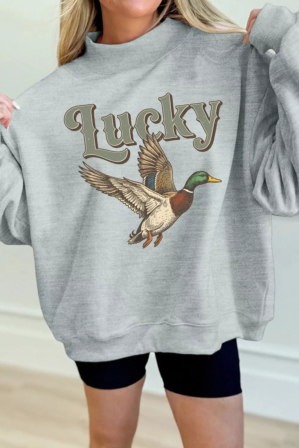 Gray lucky mallard graphic mock-neck sweatshirt, front with arms raised.