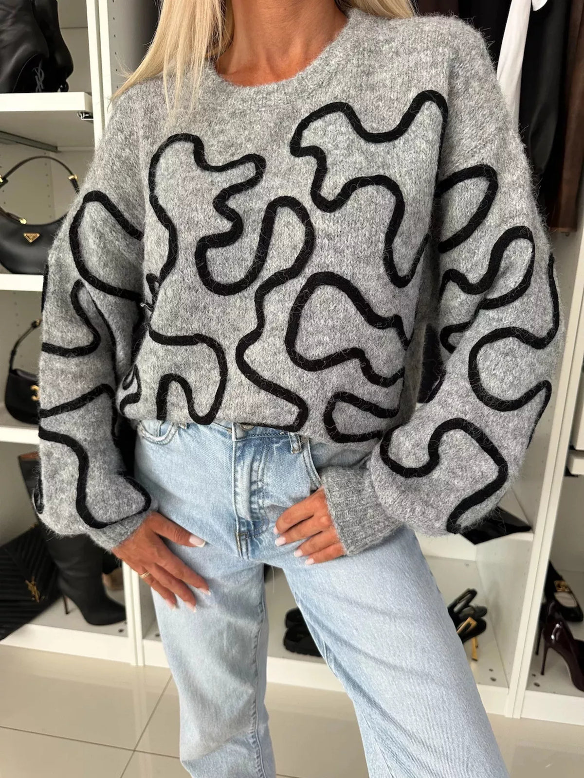 Gray abstract pattern oversized crewneck sweater, front with hands on thighs.