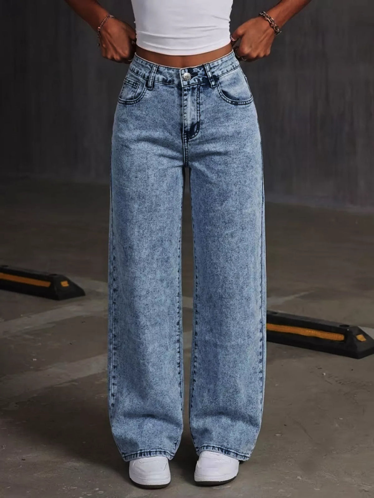 Blue bow-embroidered wide-leg jeans, front with hands at waistband.