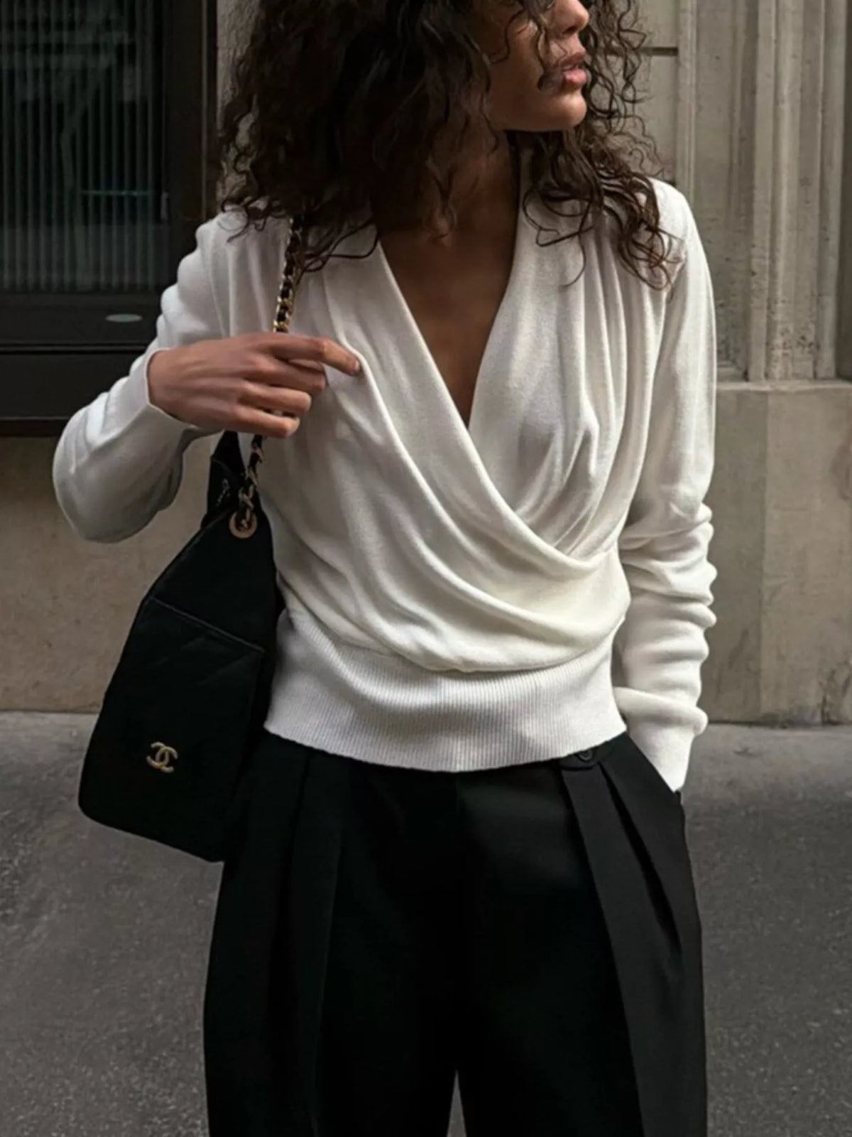 White wrap-front sweater, front view with hand raised