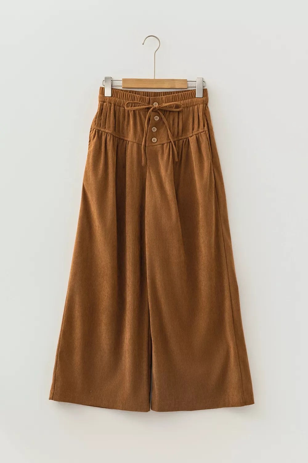 Brown button-detail wide-leg pants, front on hanger