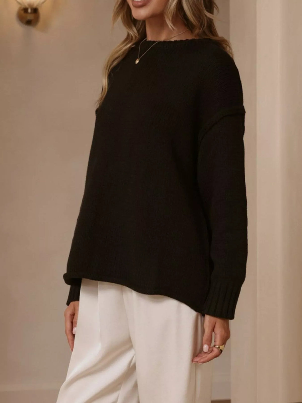 Black crewneck dropped-shoulder sweater, side view.