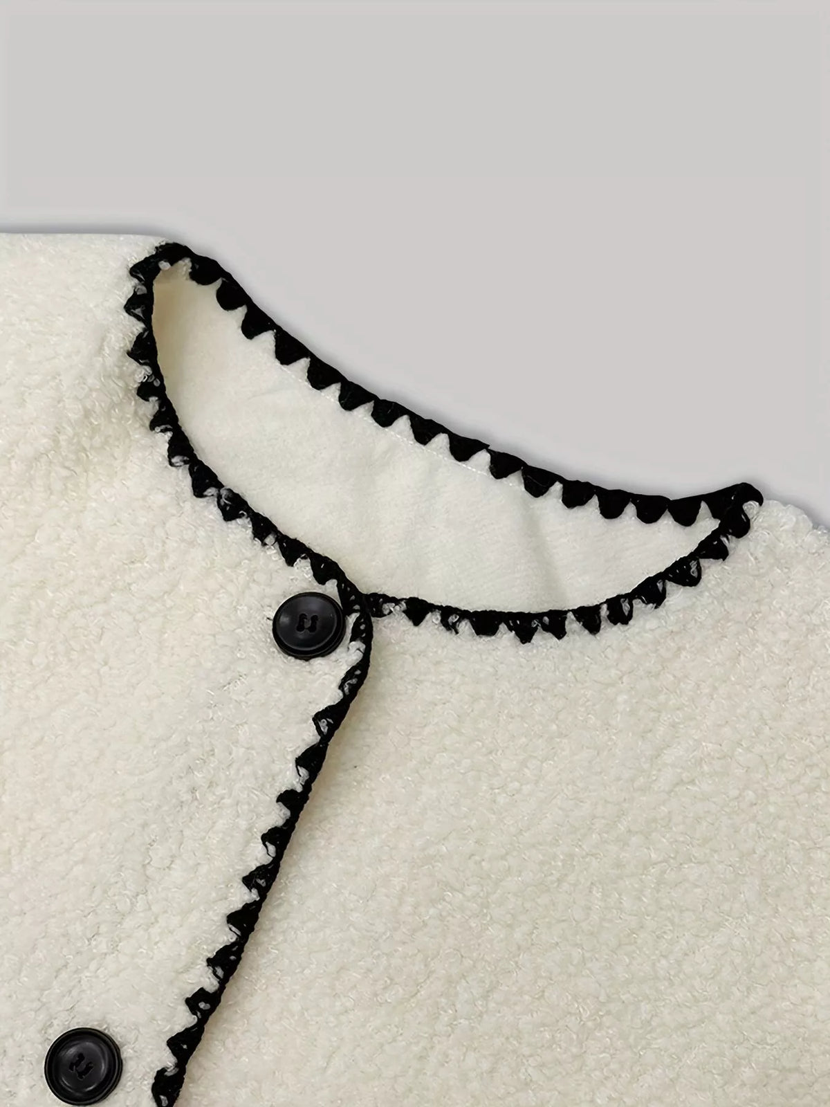 Cream with black trim faux shearling contrast trim button-down jacket, round neckline, buttons, and contrasting edge trim