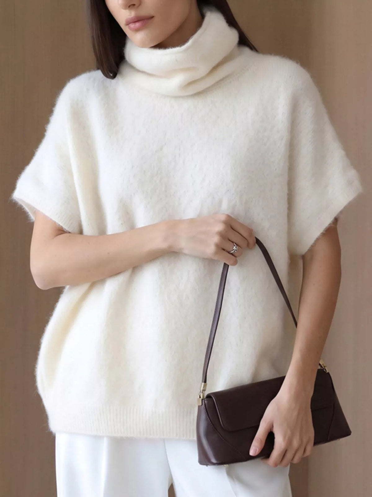 Fuzzy short-sleeve turtleneck sweater in cream, front view holding bag
