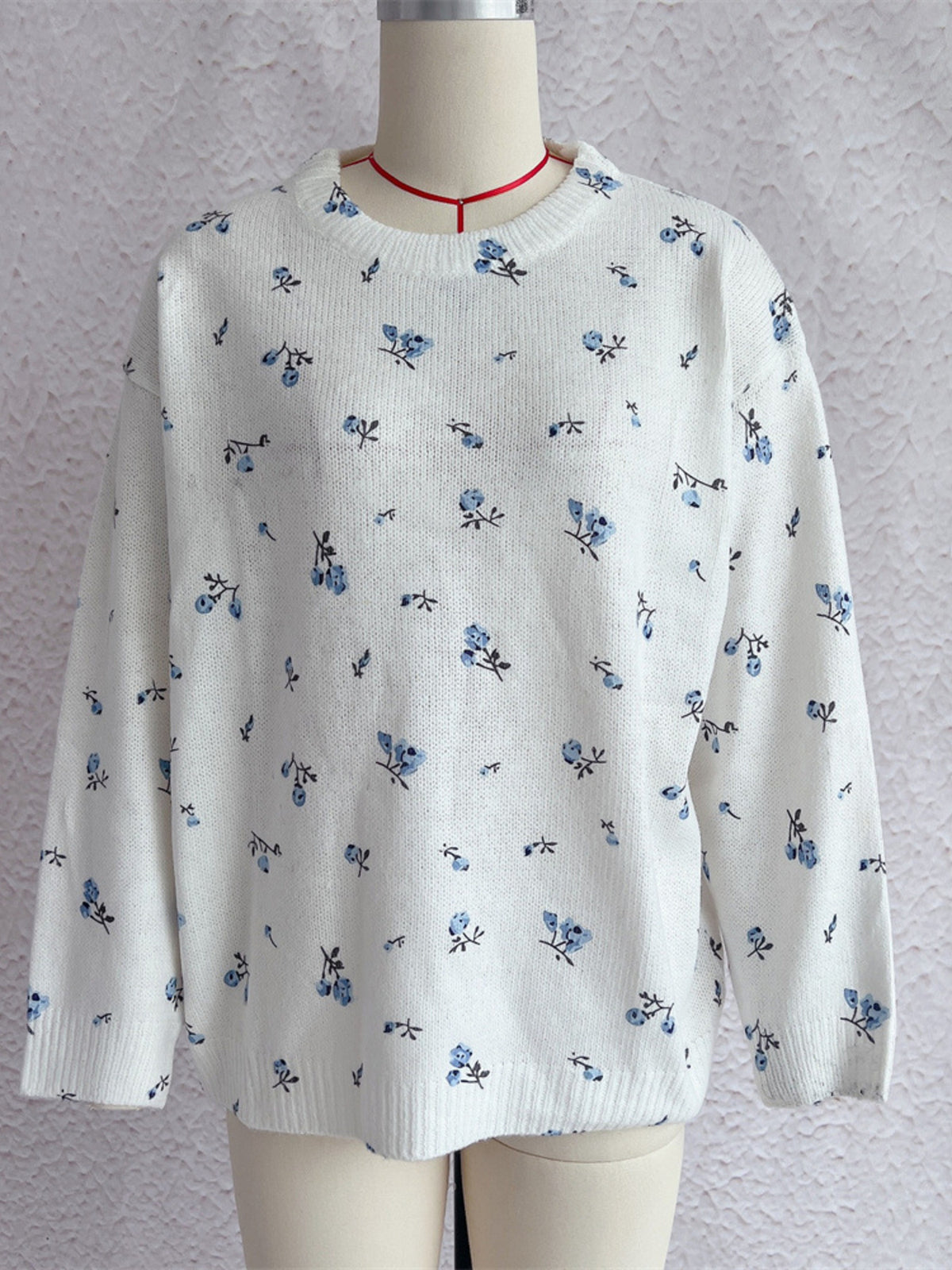 White floral dropped-shoulder oversized sweater, front on dress form.