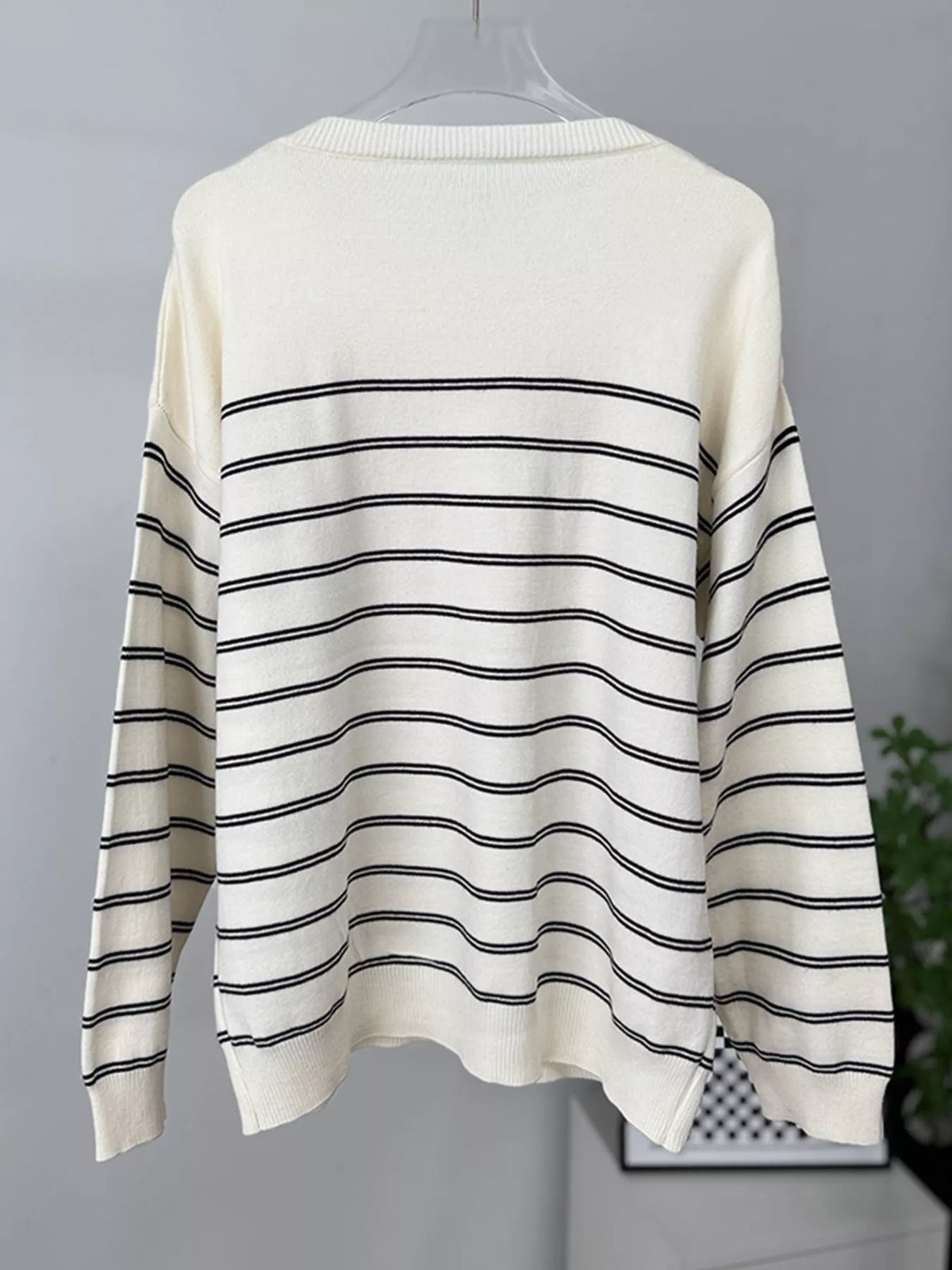 Striped crewneck sweater with layered tie detail in white and black, hanging back without layer