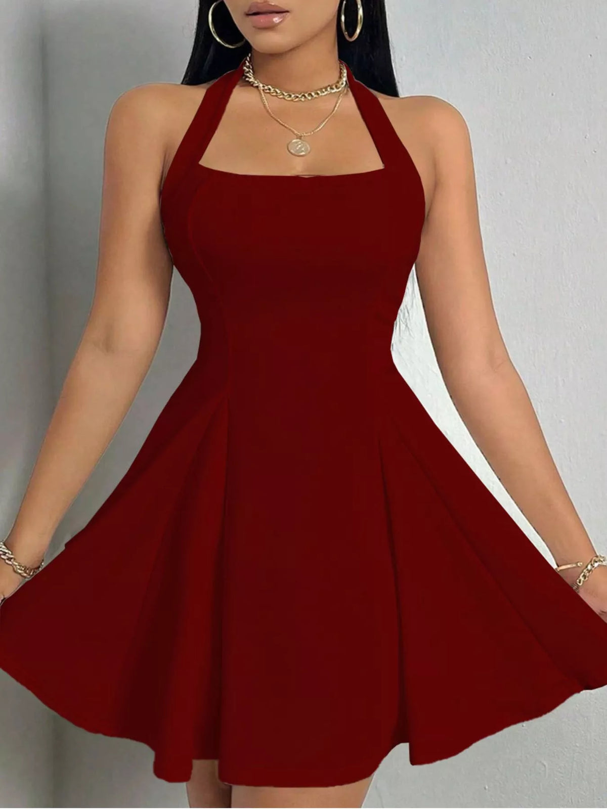 Burgundy halter-neck a-line mini dress, front holding skirt.