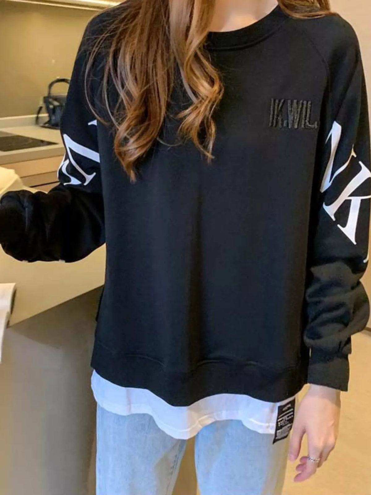 Black layered-hem sweatshirt with graphic sleeve detail, back view