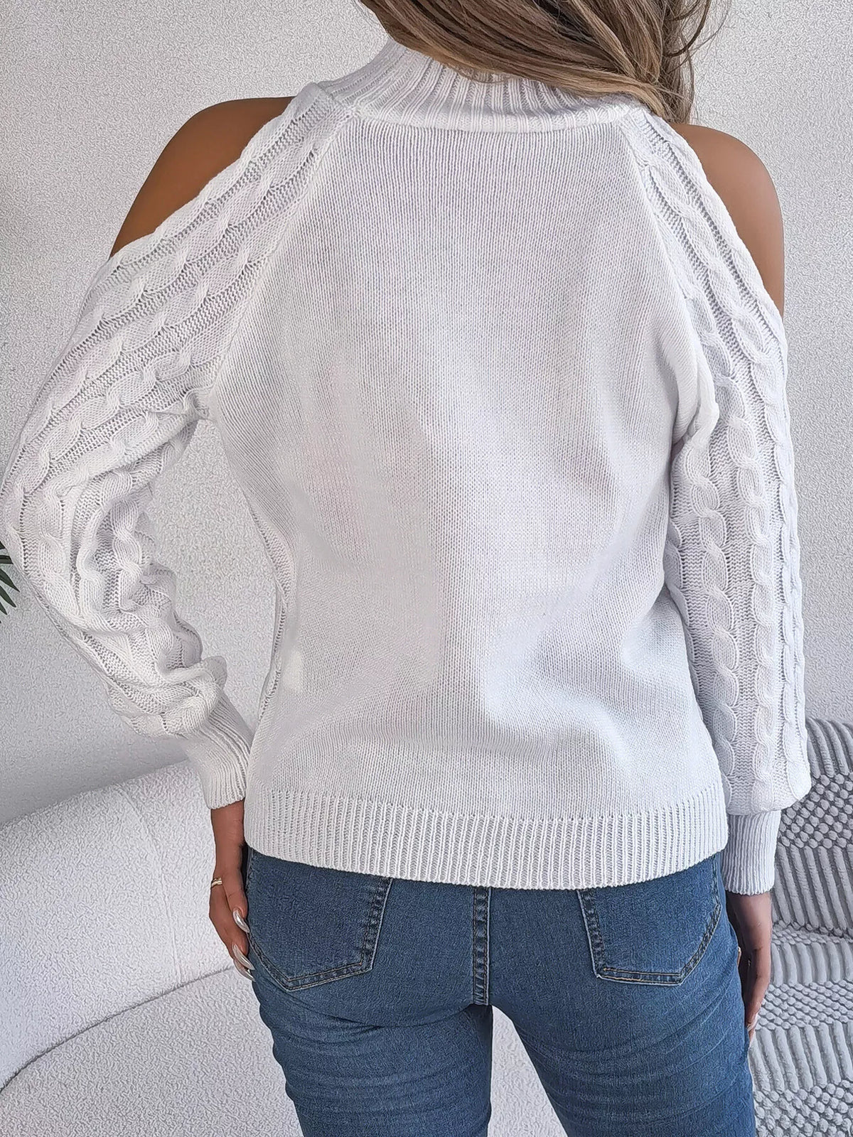 White cold-shoulder cable-knit sweater, back view.