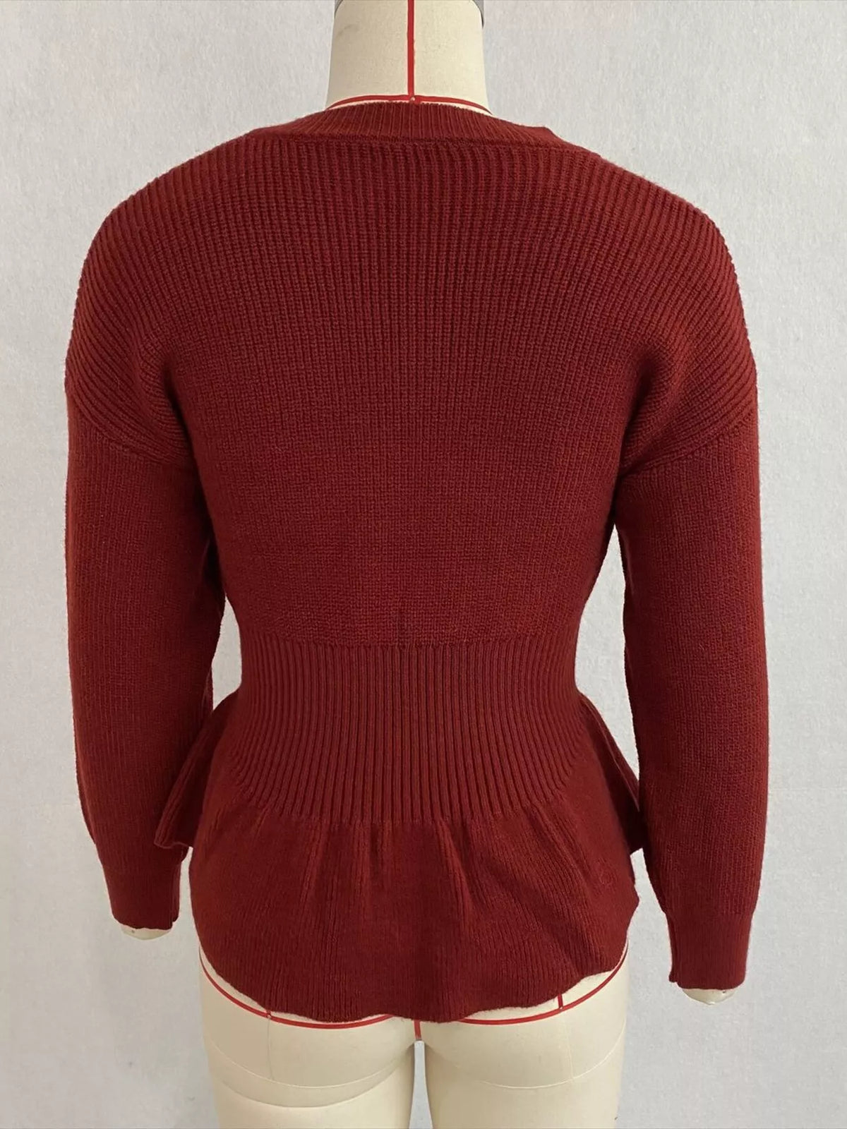 Rust v-neck peplum-hem knit sweater, back on dress form.