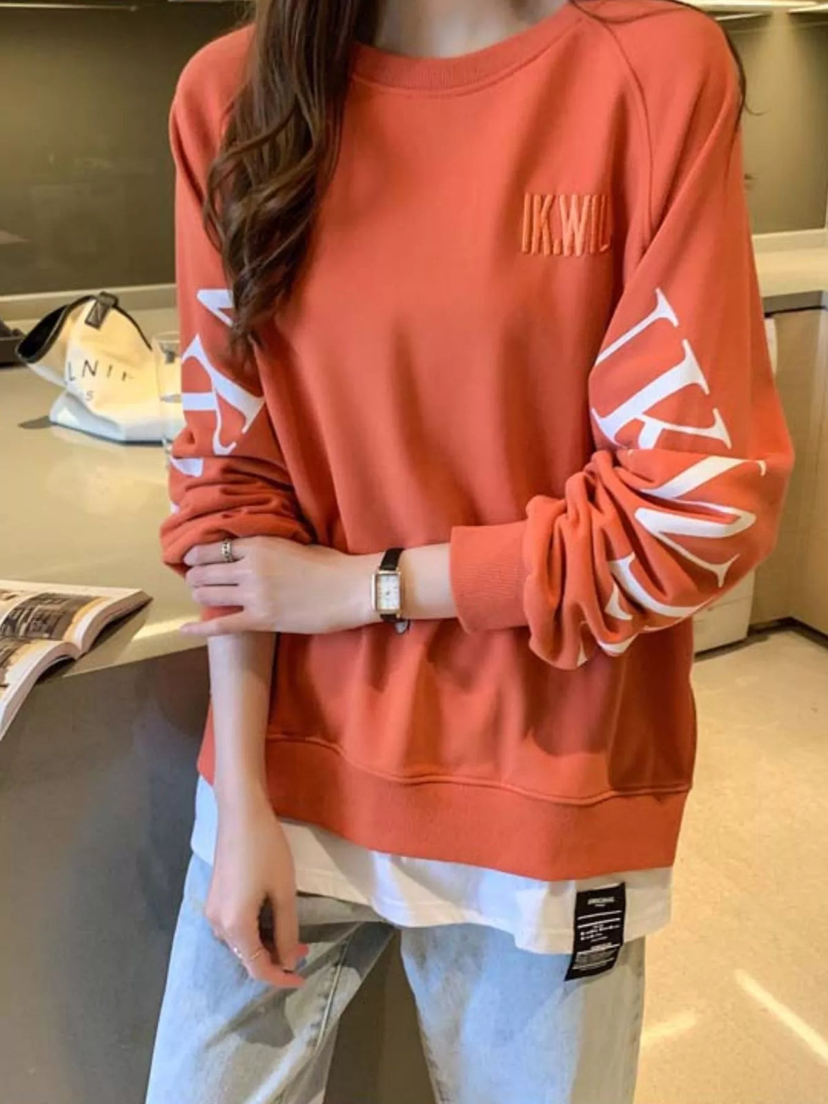 Orange layered-hem sweatshirt with graphic sleeve detail