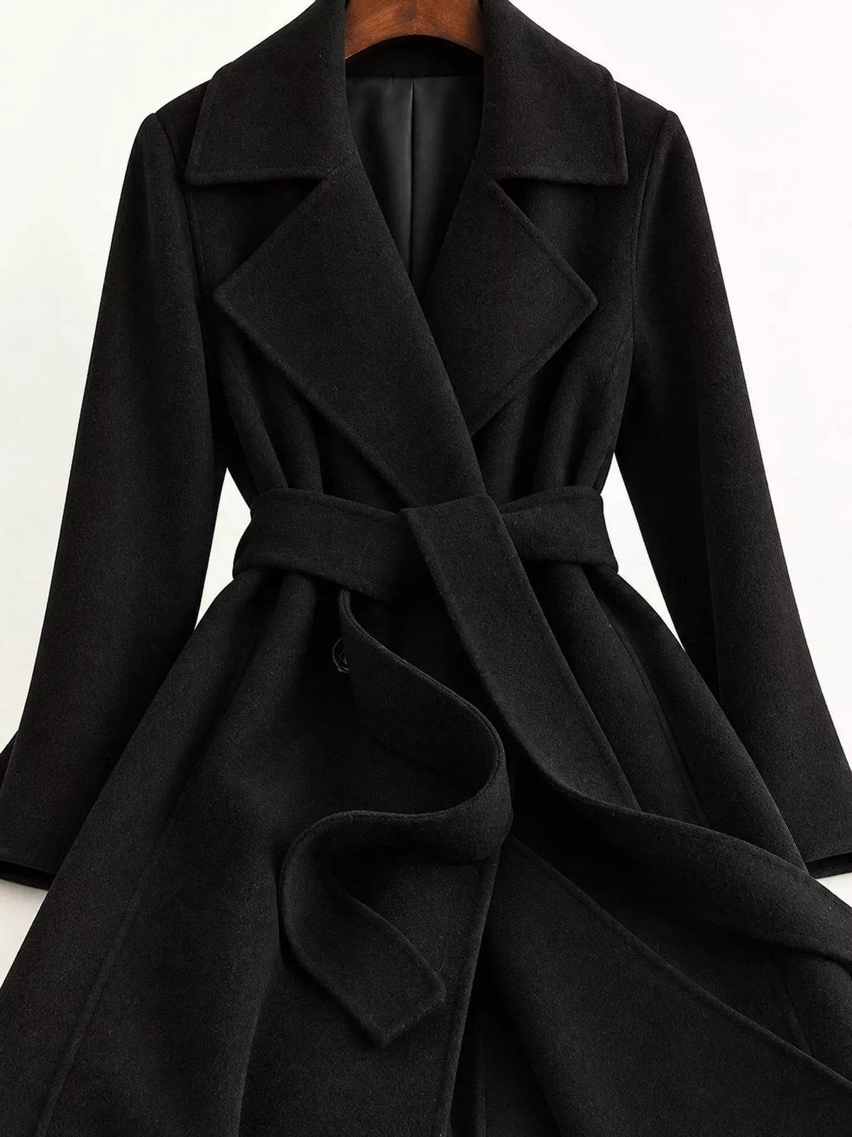 Black belted longline wool coat, notch lapels, tie belt, and side pockets