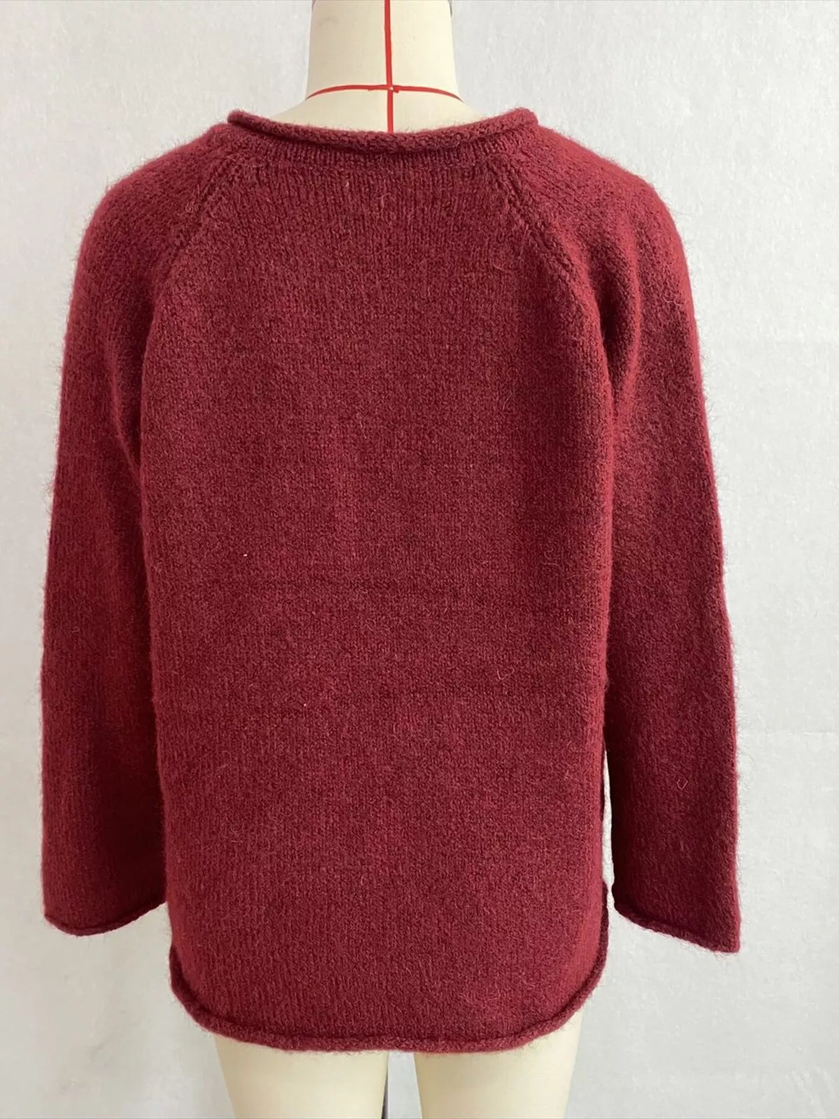 Burgundy v-neck knit top with polka dot ribbon tie, back on dress form.