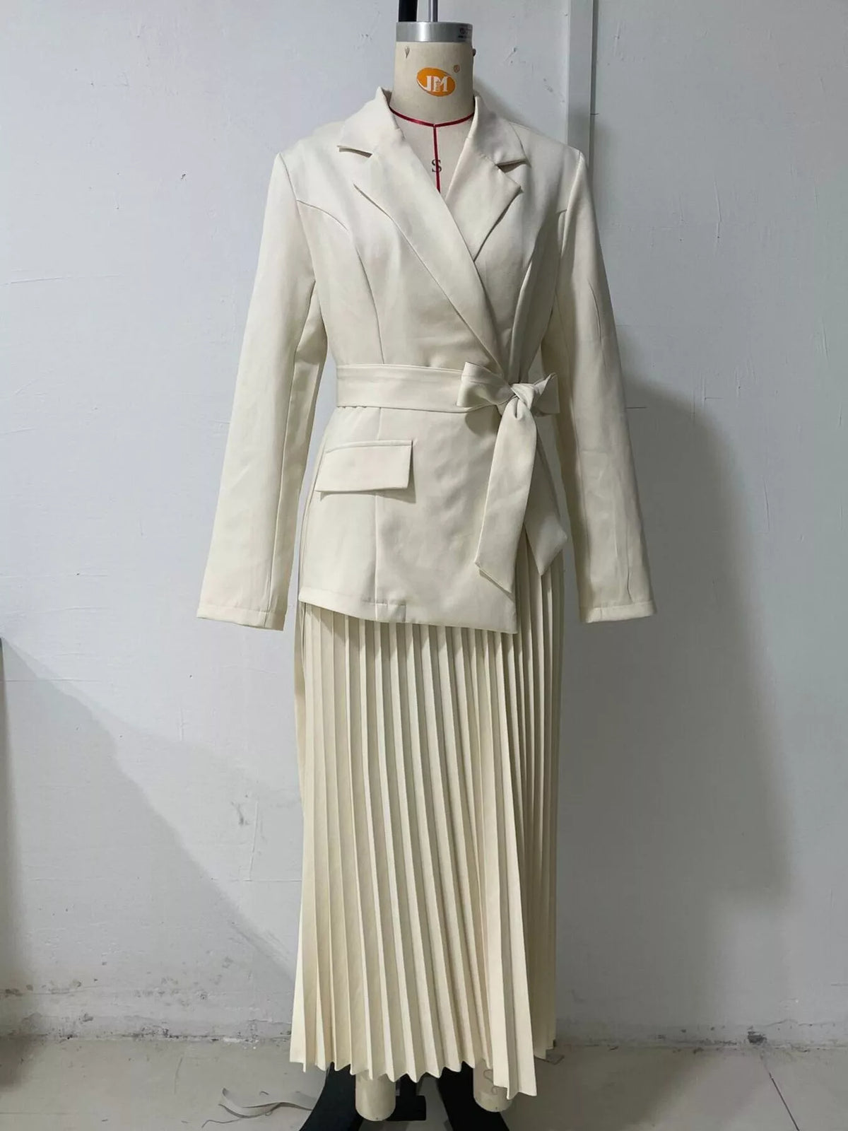 Beige belted blazer-style pleated midi dress, front on dress form