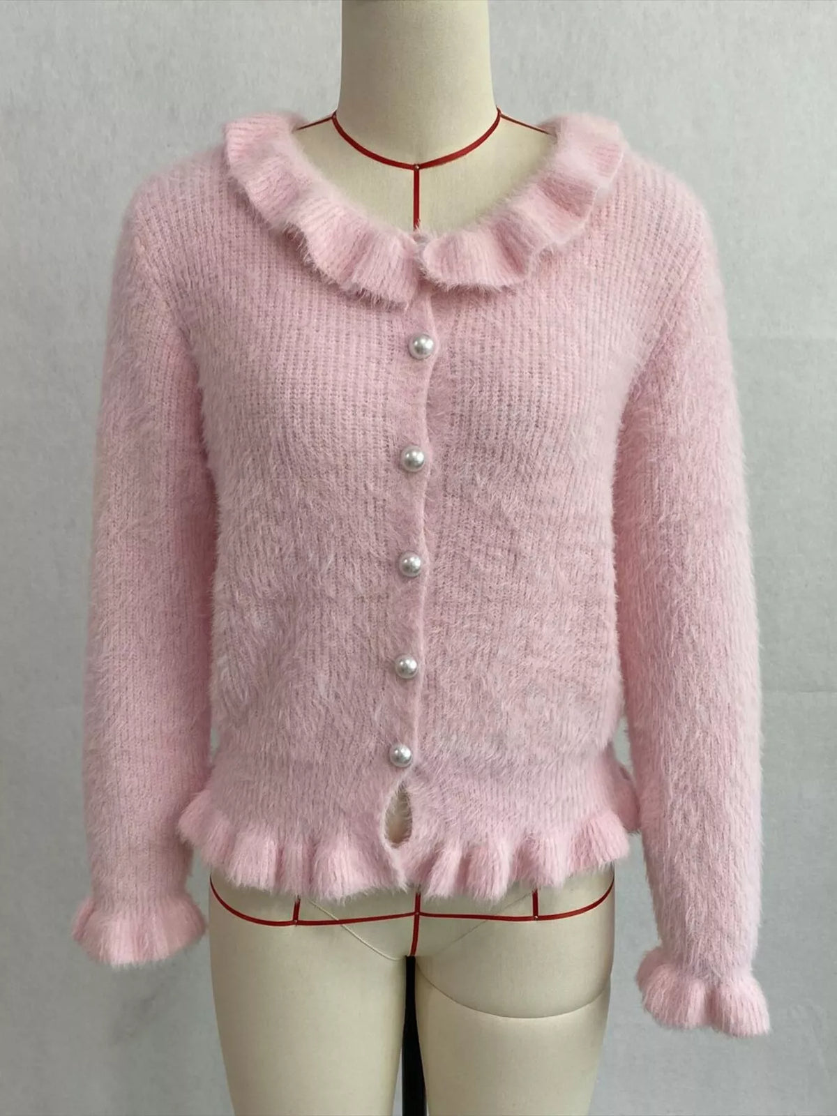 Pink fuzzy ruffle-trim button-front cardigan, front on dress form.