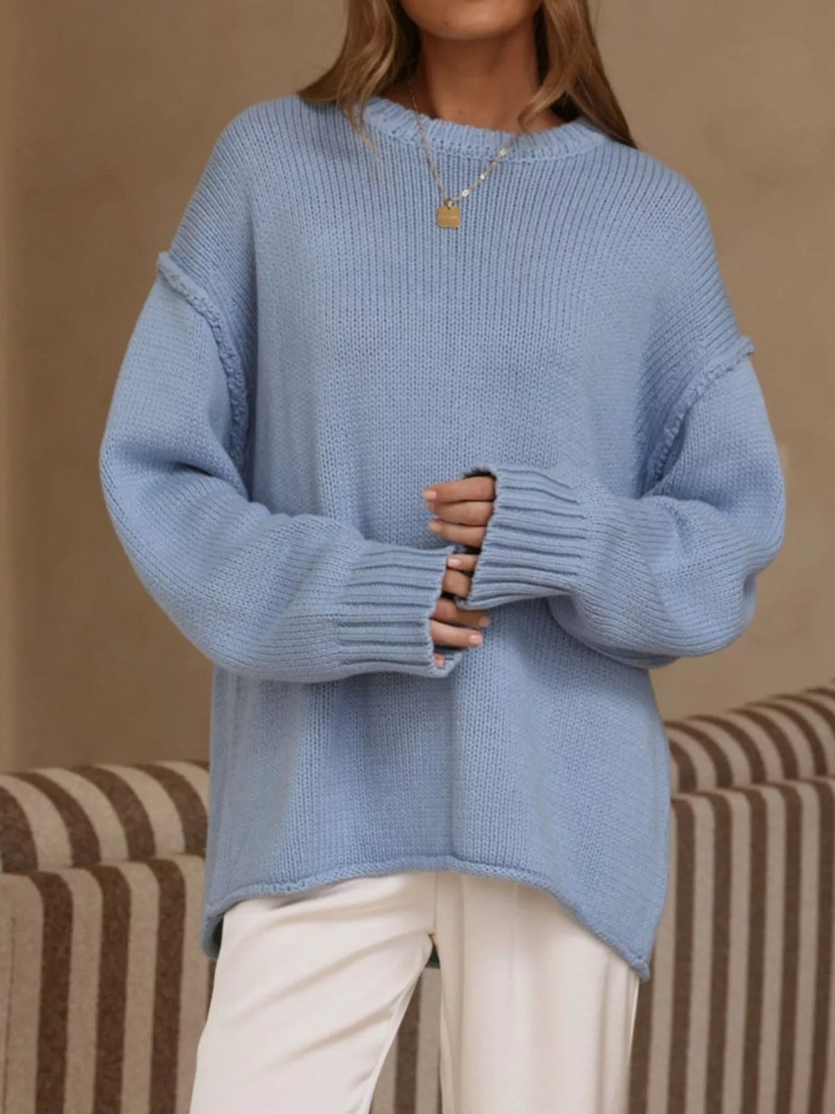Light blue crewneck dropped-shoulder sweater, front with hands at cuffs.
