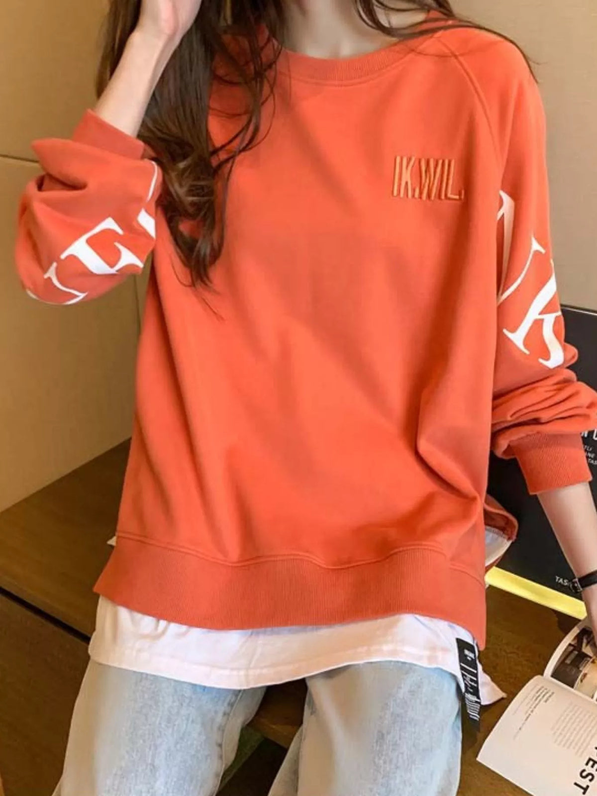 Orange layered-hem sweatshirt with graphic sleeve detail