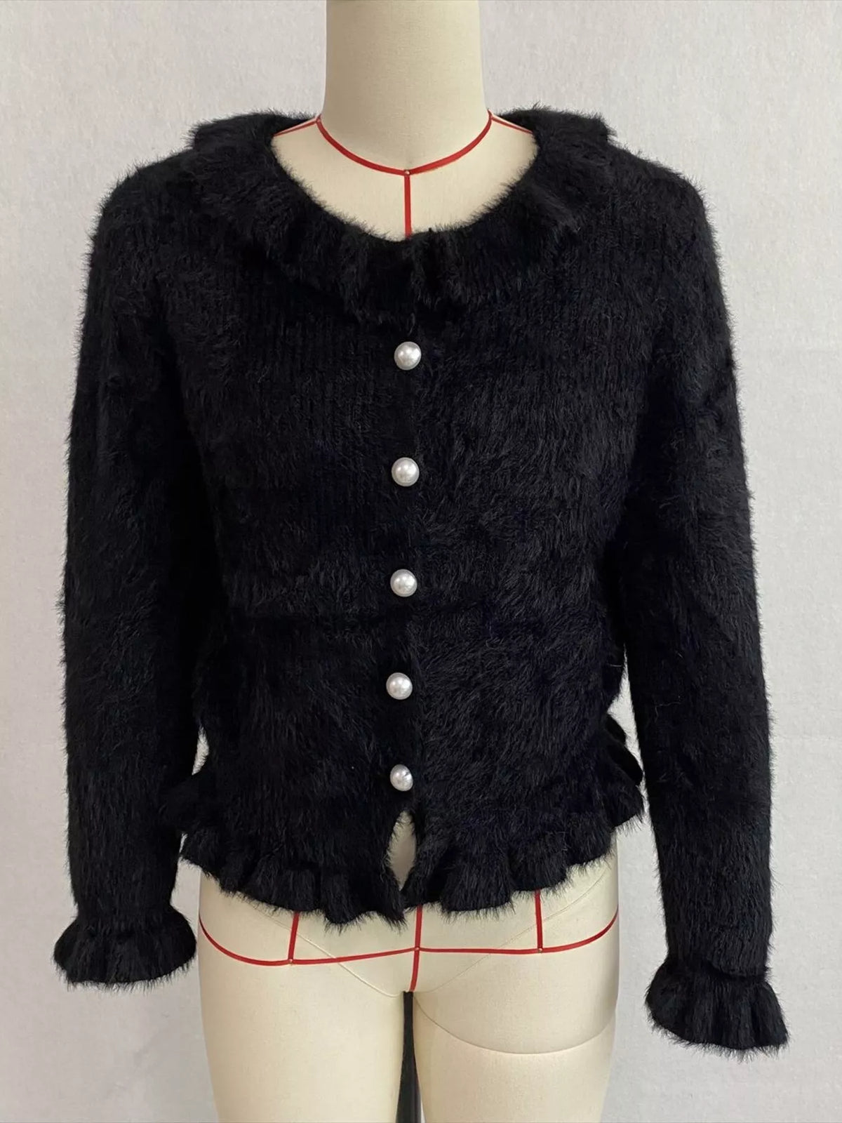 Black fuzzy ruffle-trim button-front cardigan, front on dress form.