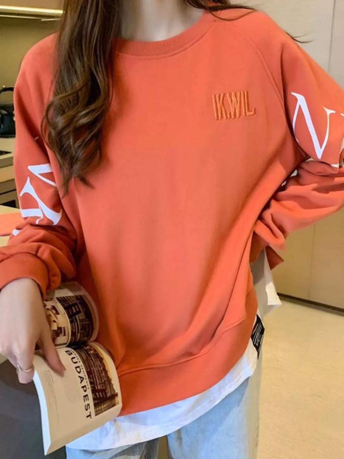 Orange layered-hem sweatshirt with graphic sleeve detail