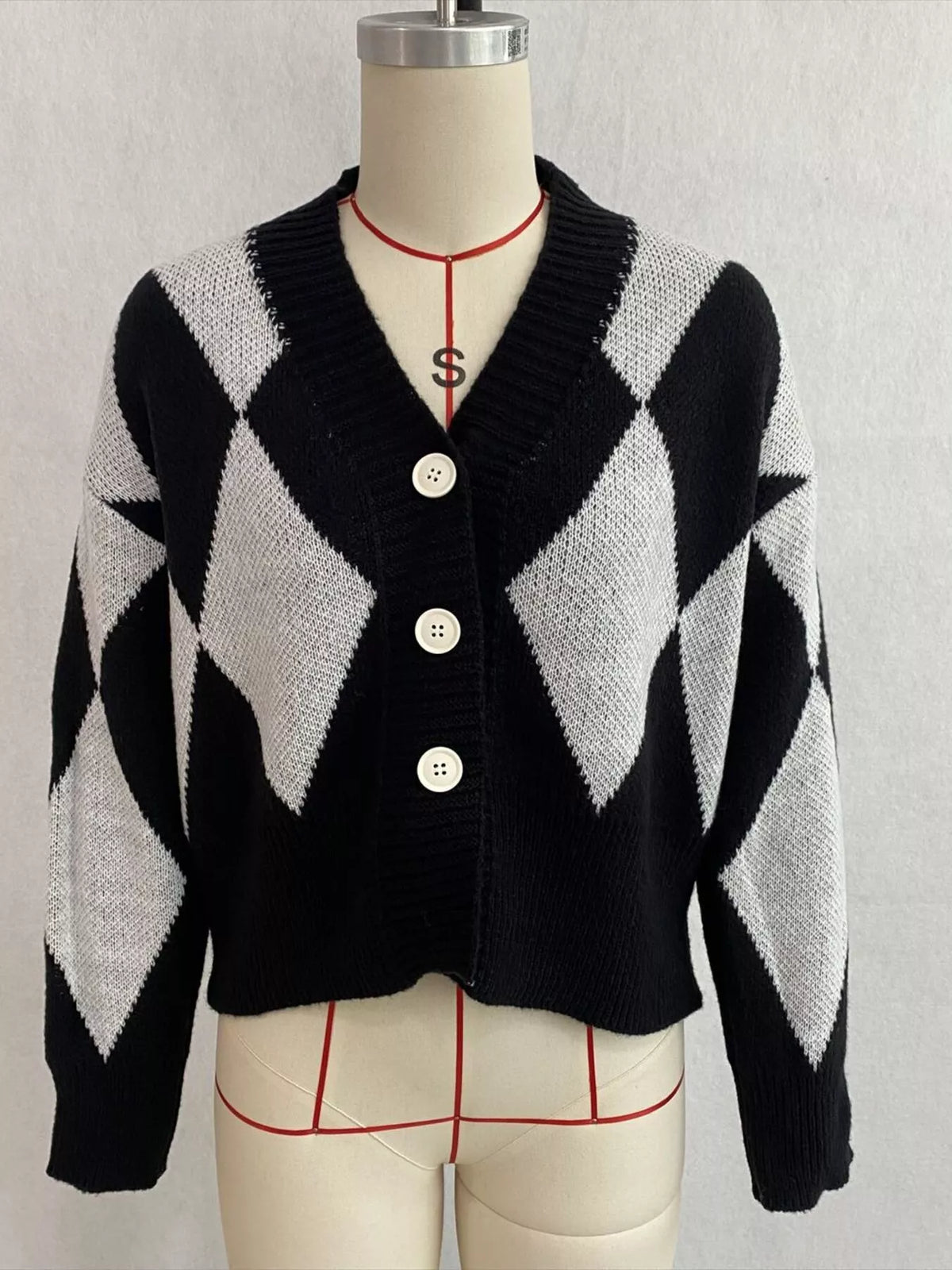 Black and white argyle v-neck button-front cardigan, front on dress form.