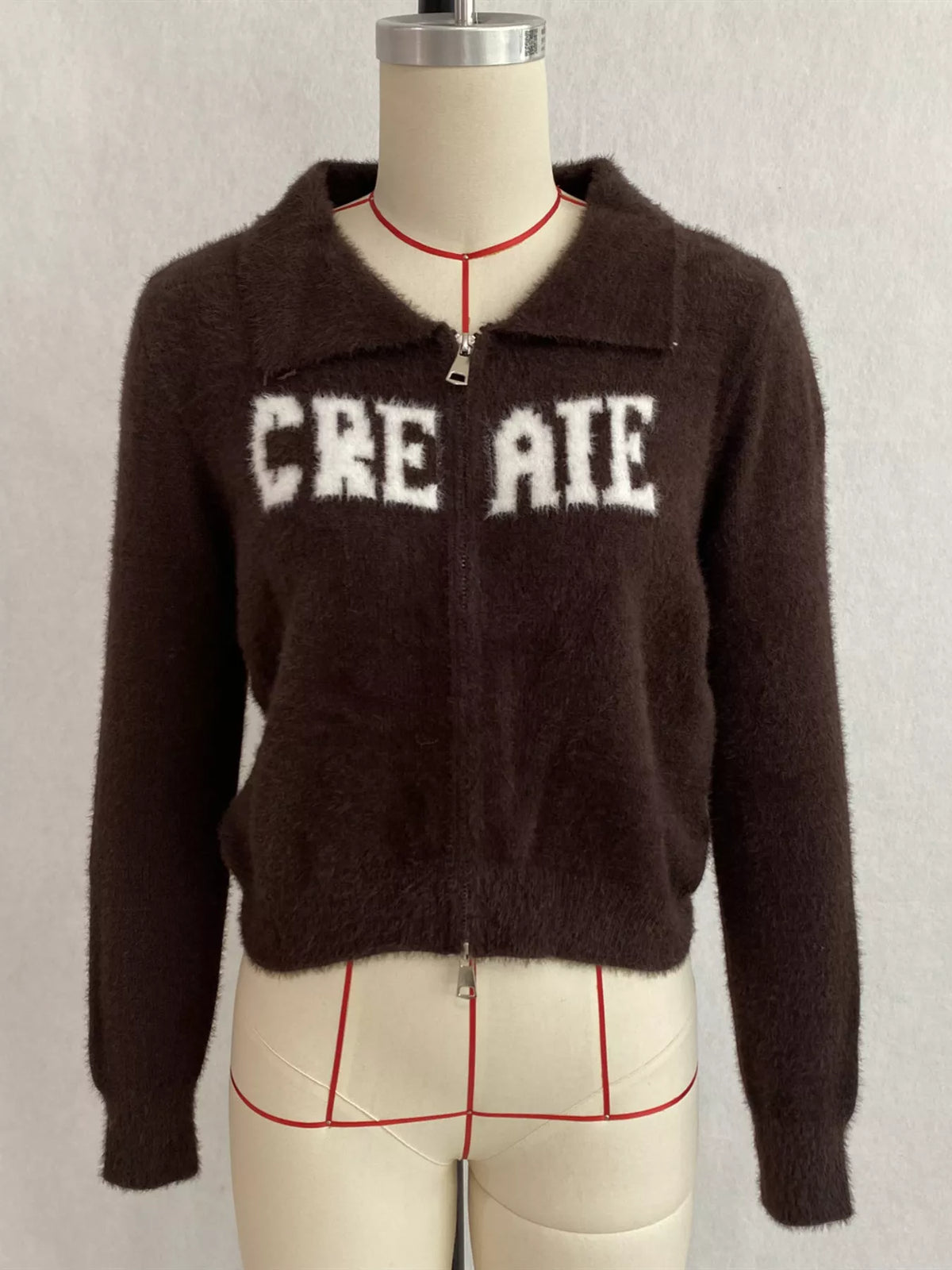 Brown fuzzy letter zip-up cardigan, front on dress form.
