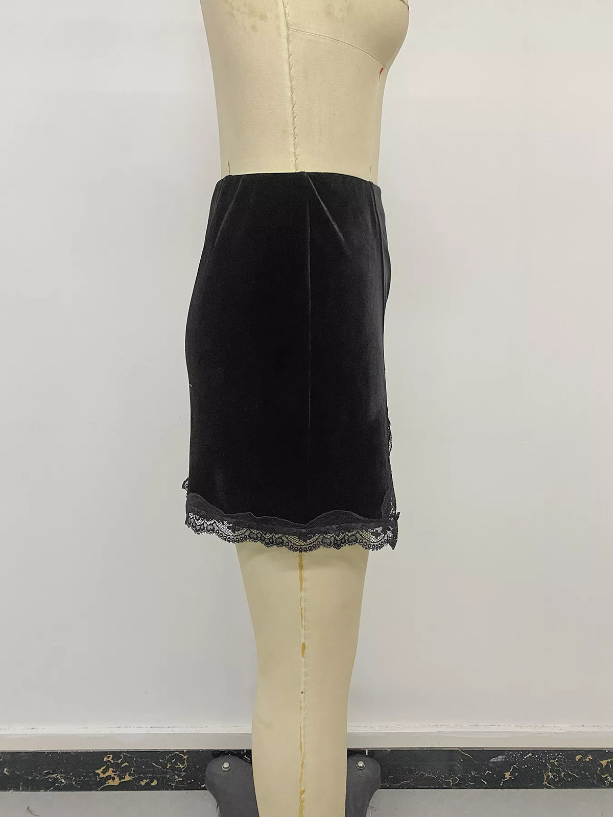 Black velvet mini skirt with lace trim, side on mannequin