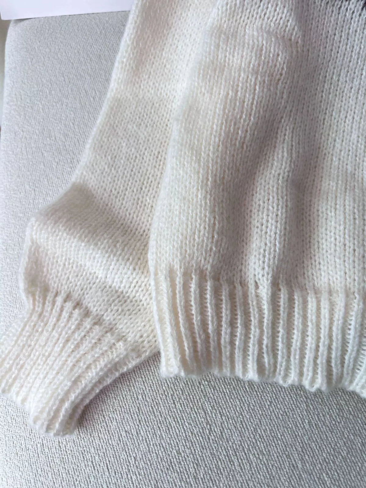 Cream fair isle round-neck sweater, ribbed cuff detail.