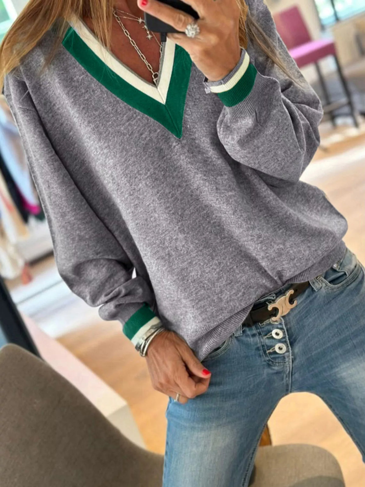 Gray v-neck sweater with striped trim, front view showing striped cuffs.