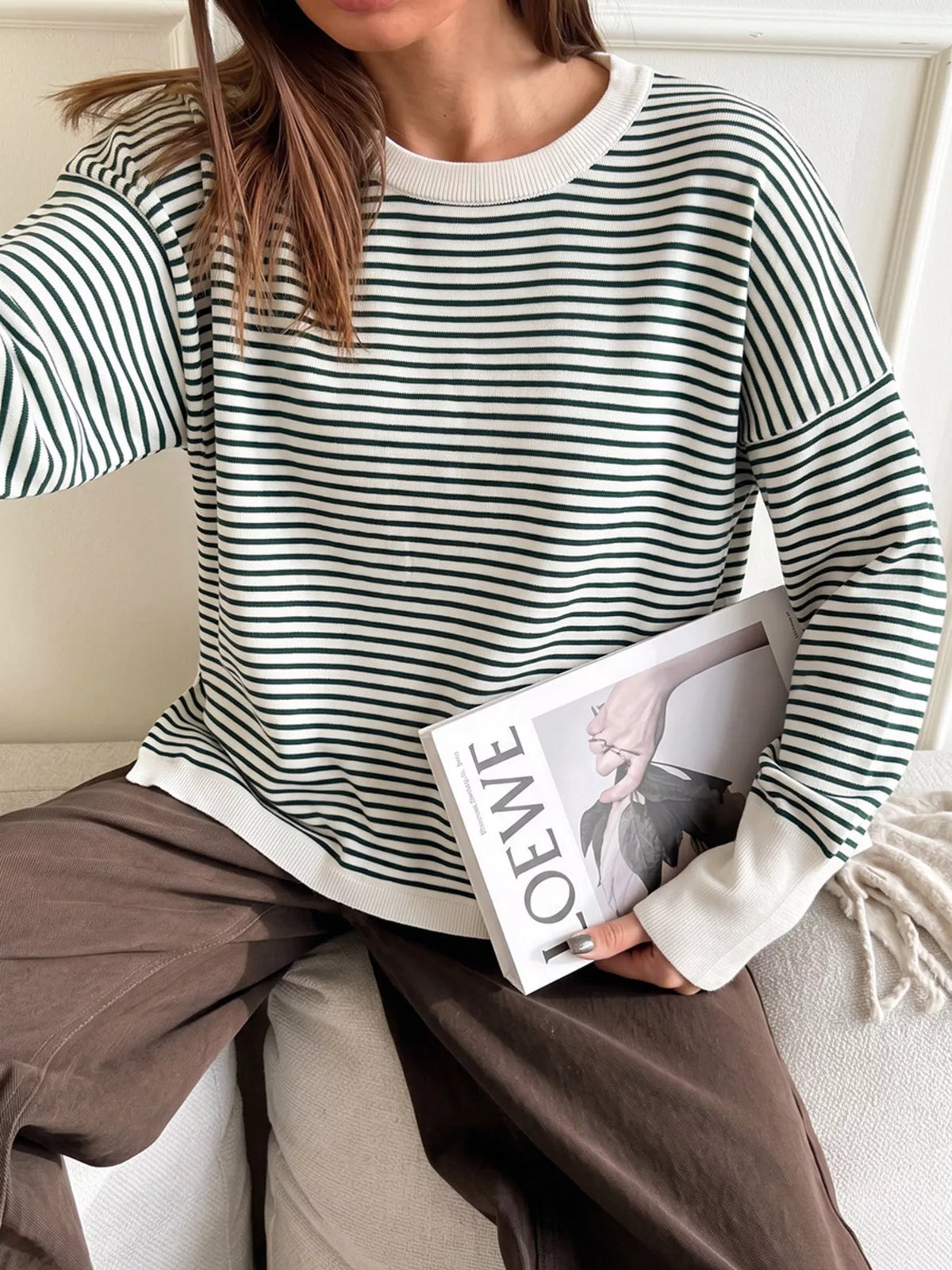 Striped round-neck knit top in white and green, seated front view