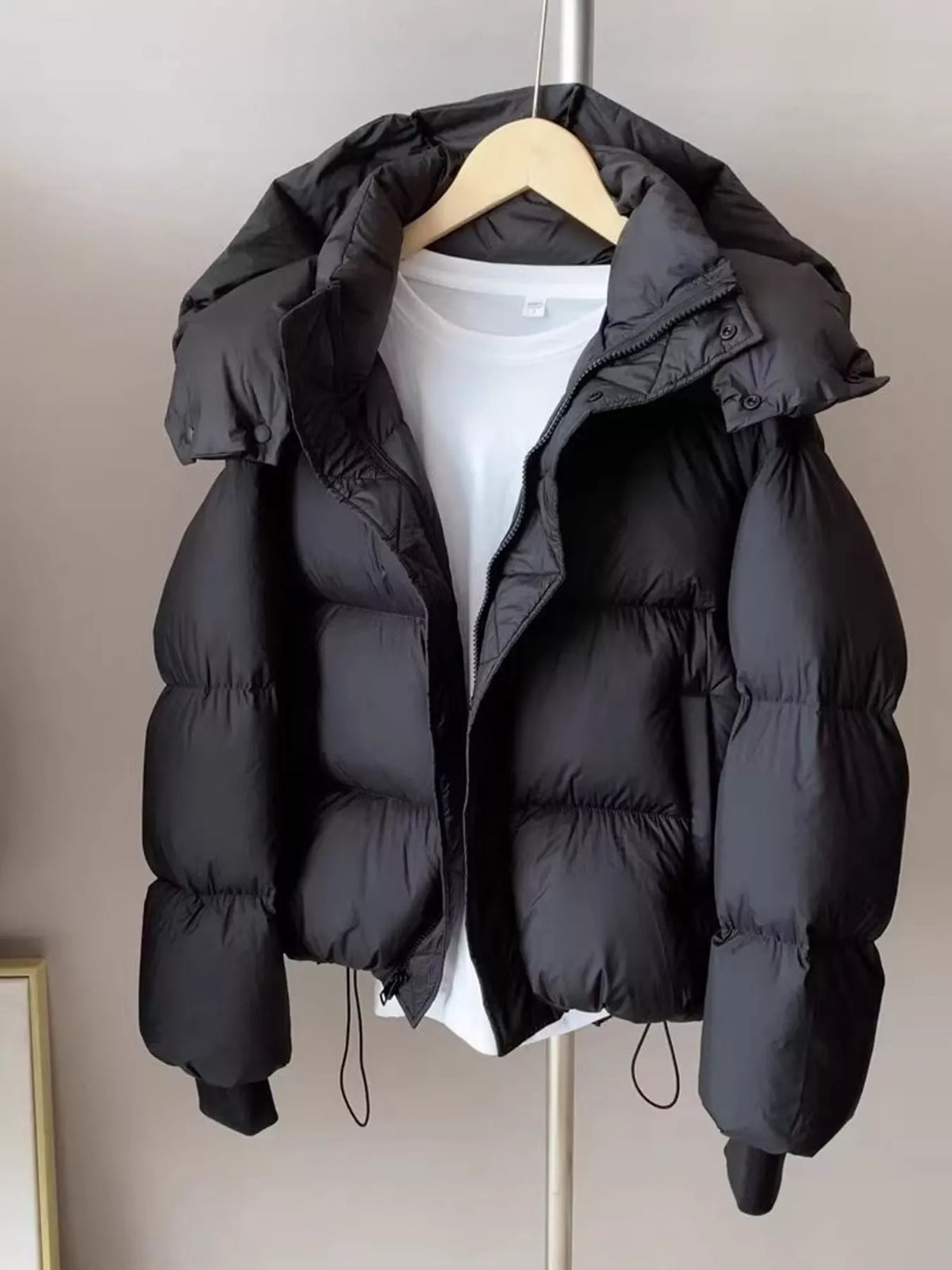 Black quilted hooded puffer jacket, front on hanger