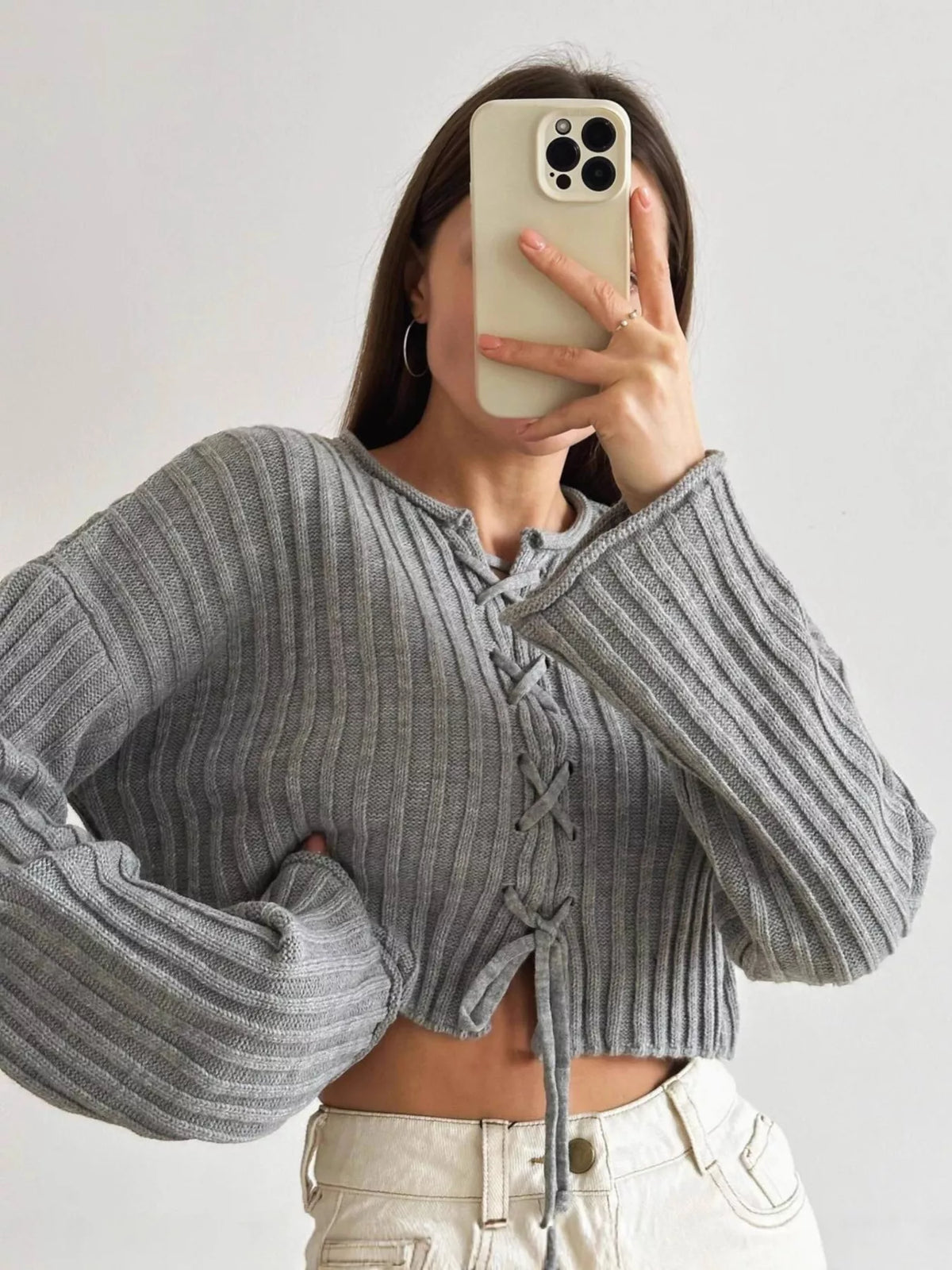 Gray ribbed lace-up cropped sweater, front with raised arm.