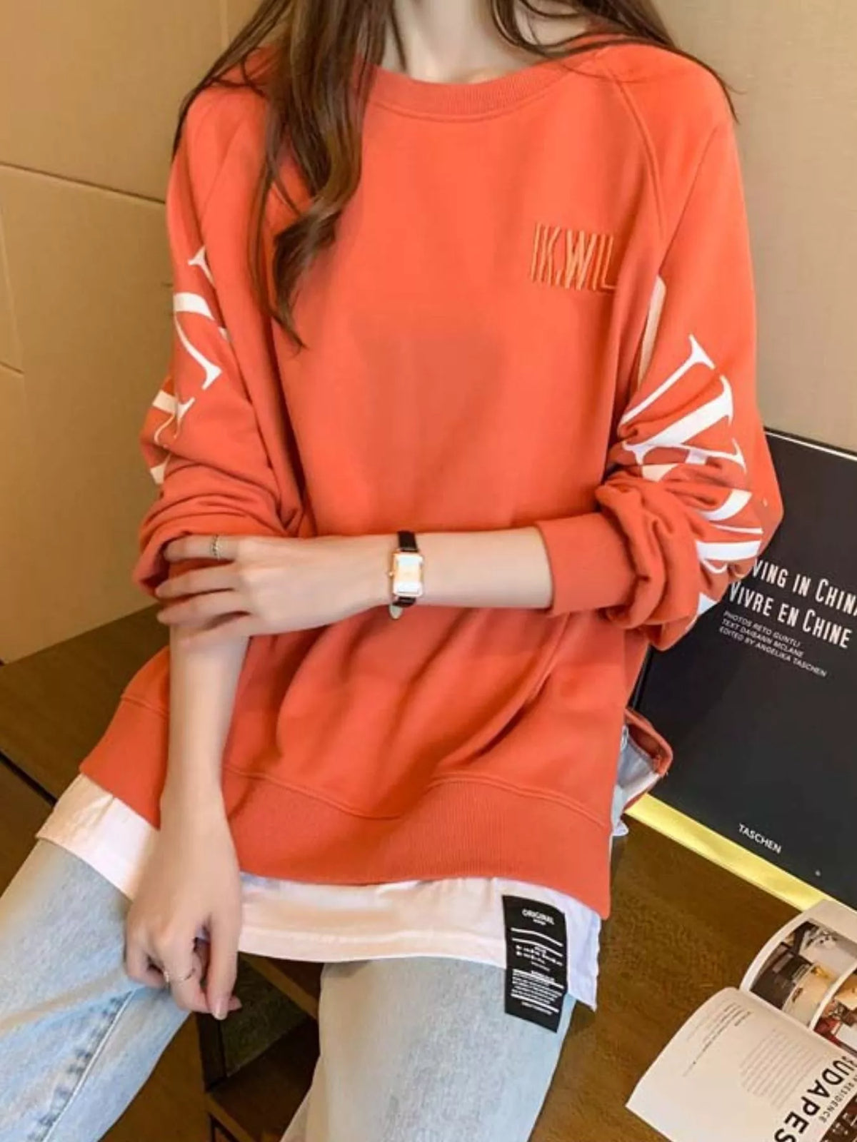Orange layered-hem sweatshirt with graphic sleeve detail