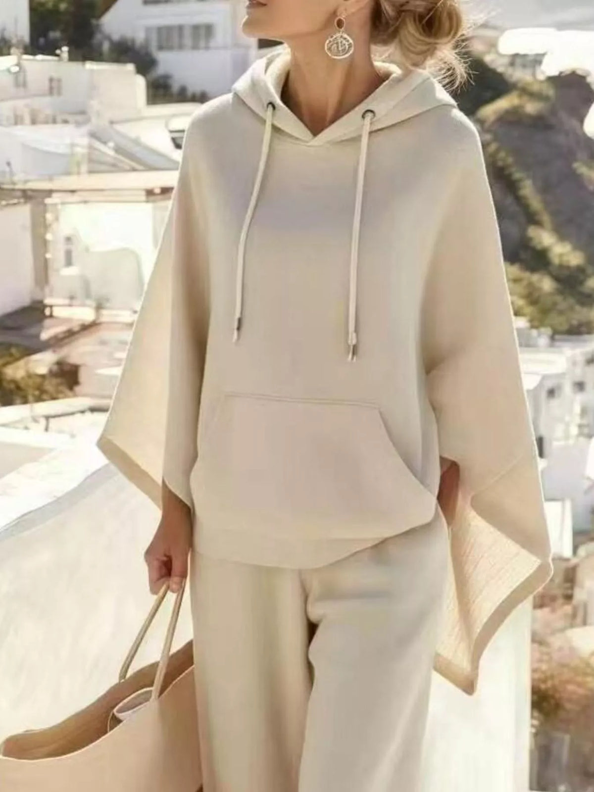 Cream hooded poncho and wide-leg pants set, poncho and front pocket detail.