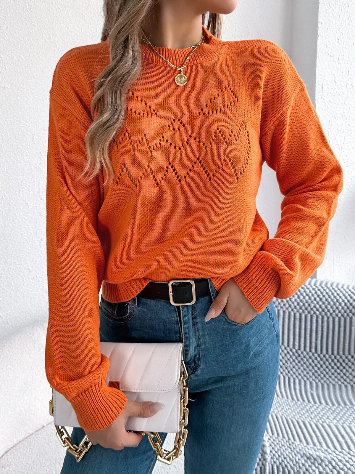 Orange halloween pumpkin face knit sweater, front with handbag.