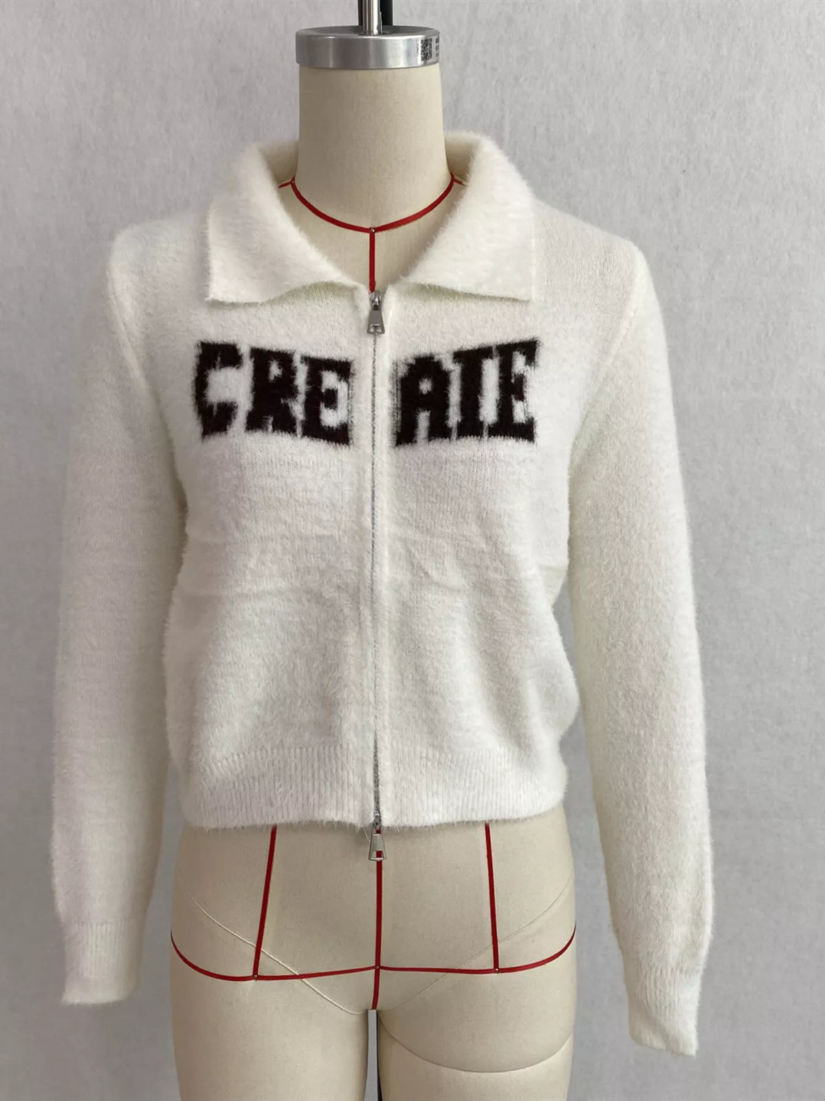 White fuzzy letter zip-up cardigan, front on dress form.